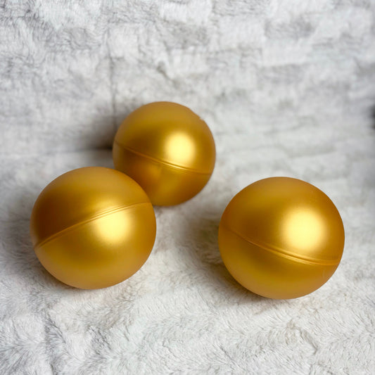 Three gold spherical objects on a textured white surface