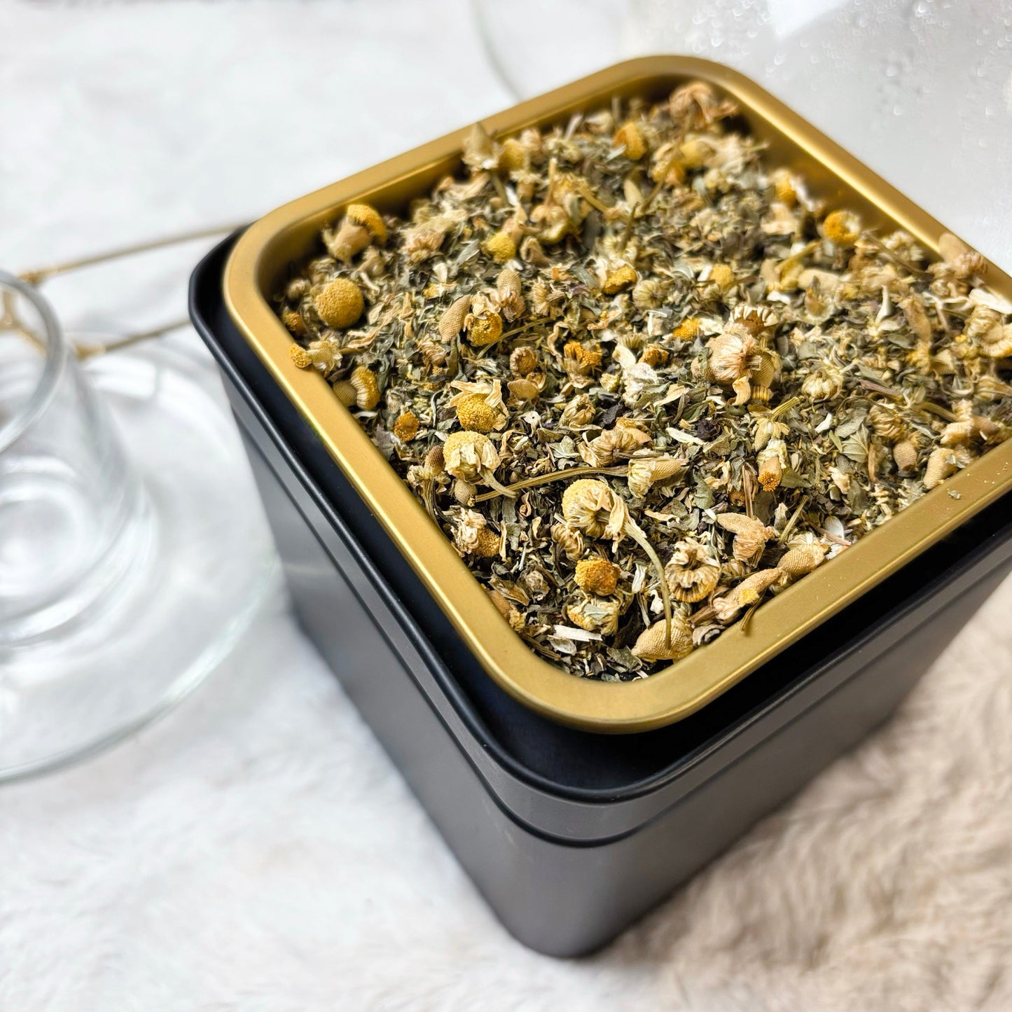 Square container with dried herbs on a white surface