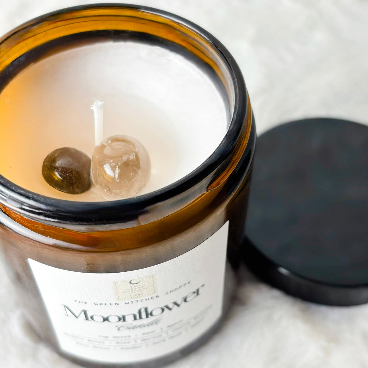 Candle in an amber jar labeled 'Moonflower' on a white surface