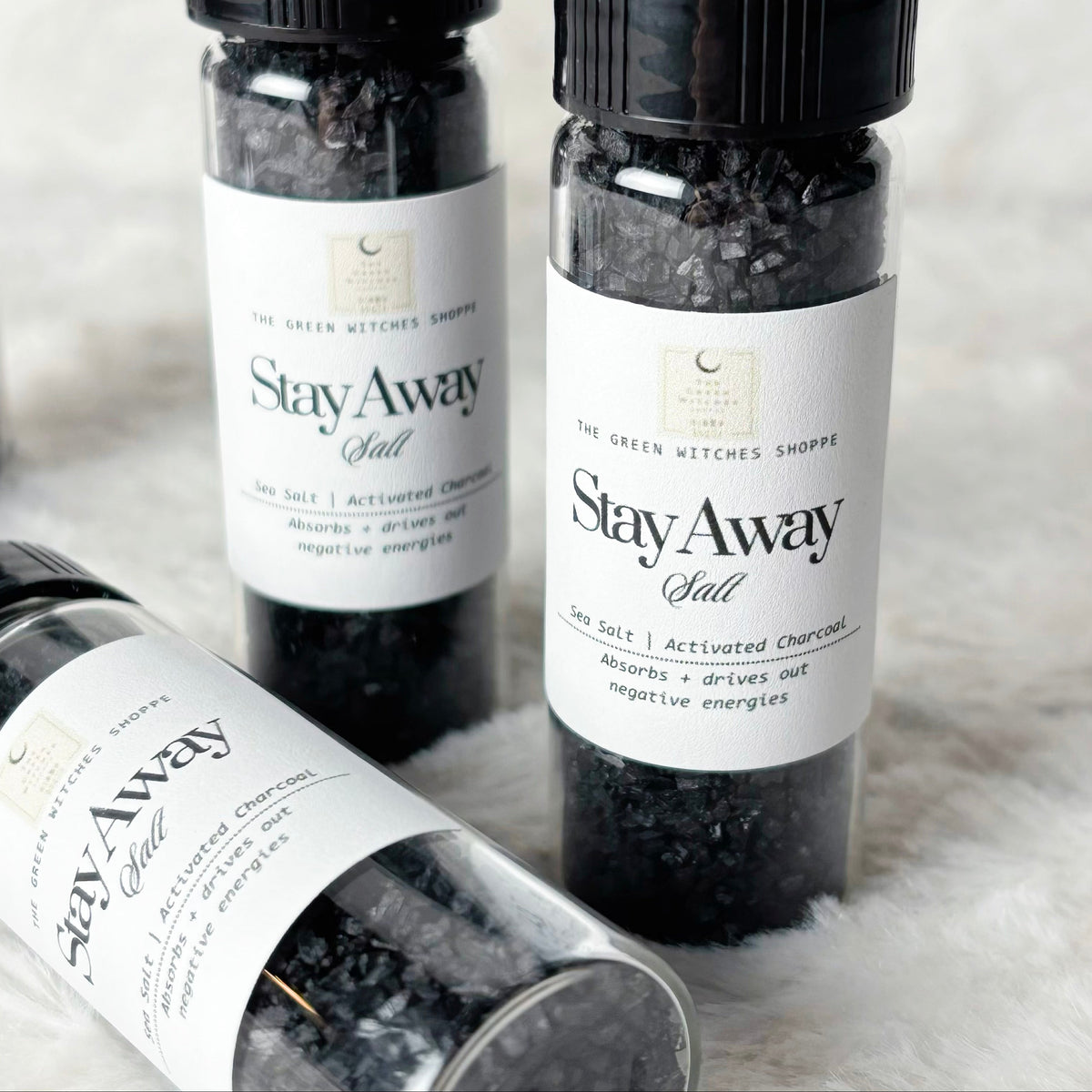 Four bottles of 'Stay Away Salt' on a textured surface