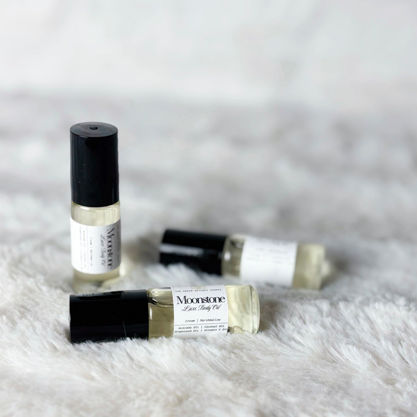 Three small glass bottles with black caps on a white fluffy surface