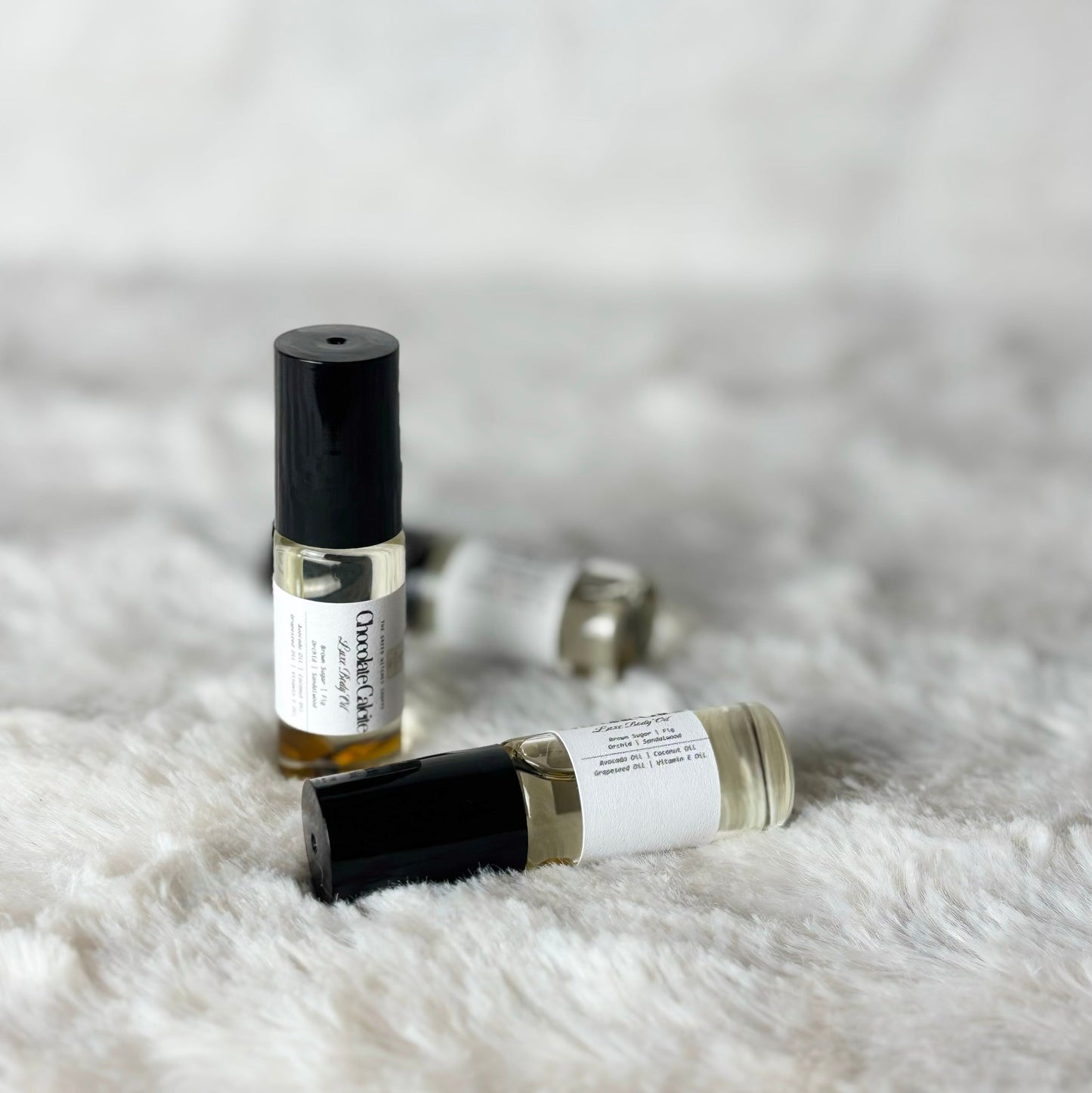Two small perfume bottles on a textured white surface