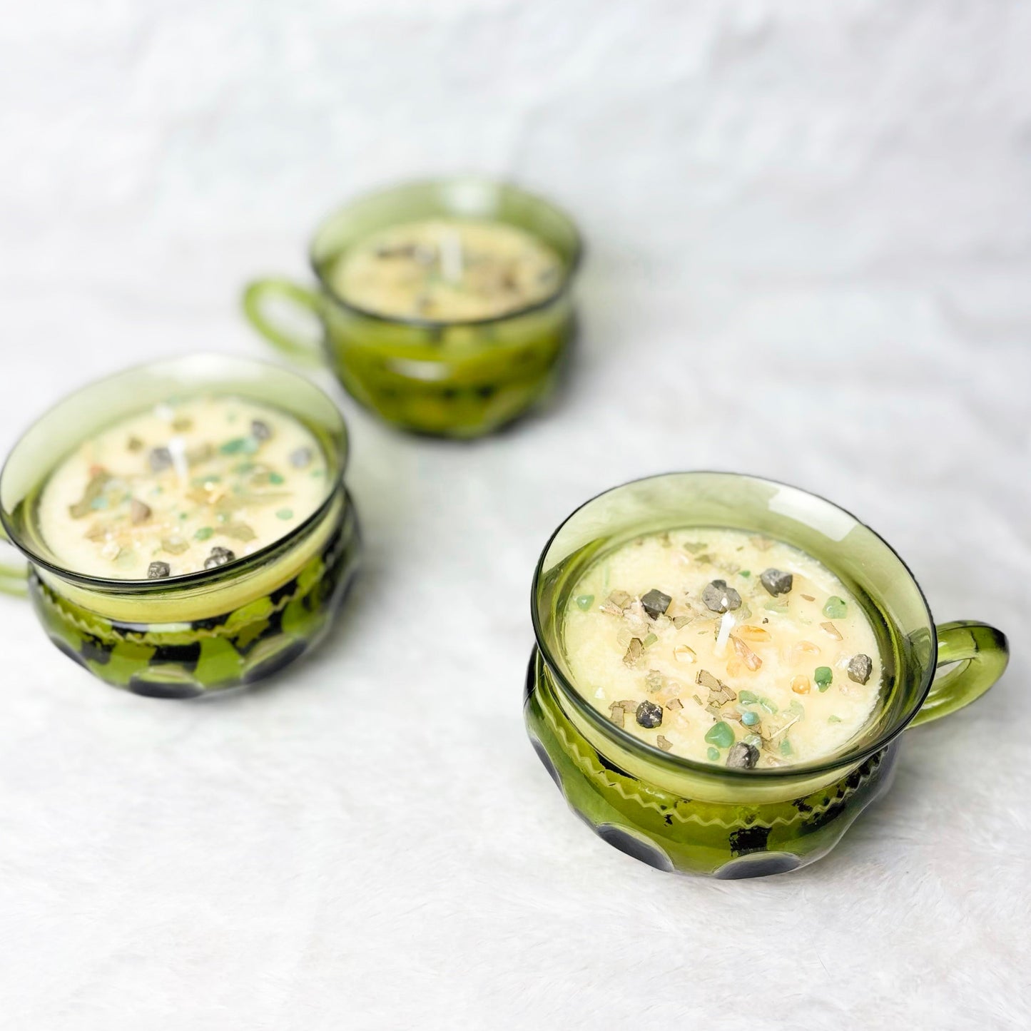 Candles with stones in a green glass cup