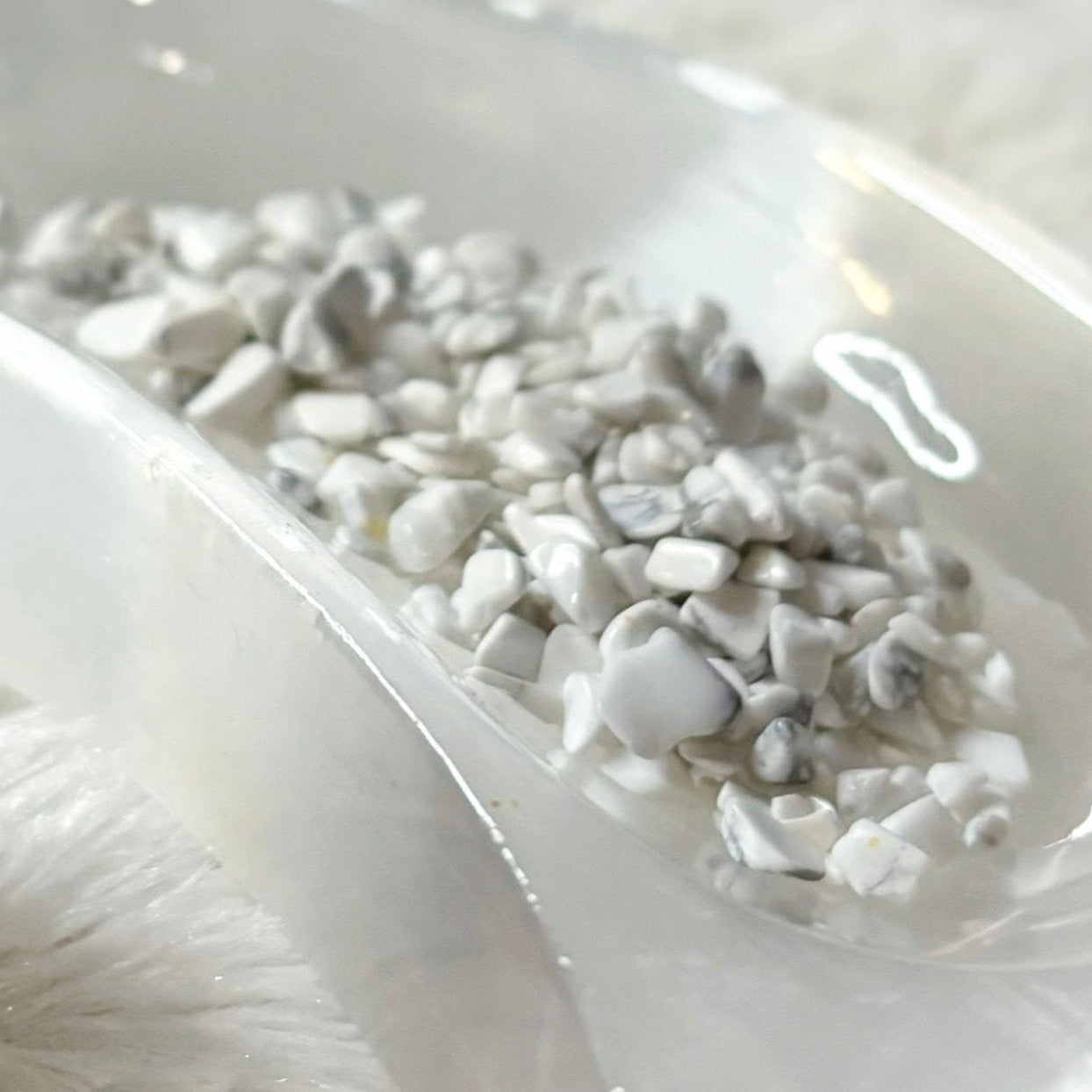 Small glass bottle labeled 'Howlite' with stones on a white surface