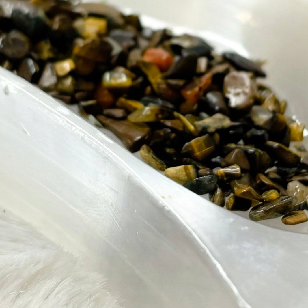 Tiger's Eye essential oil bottle with a bowl of stones on a white surface