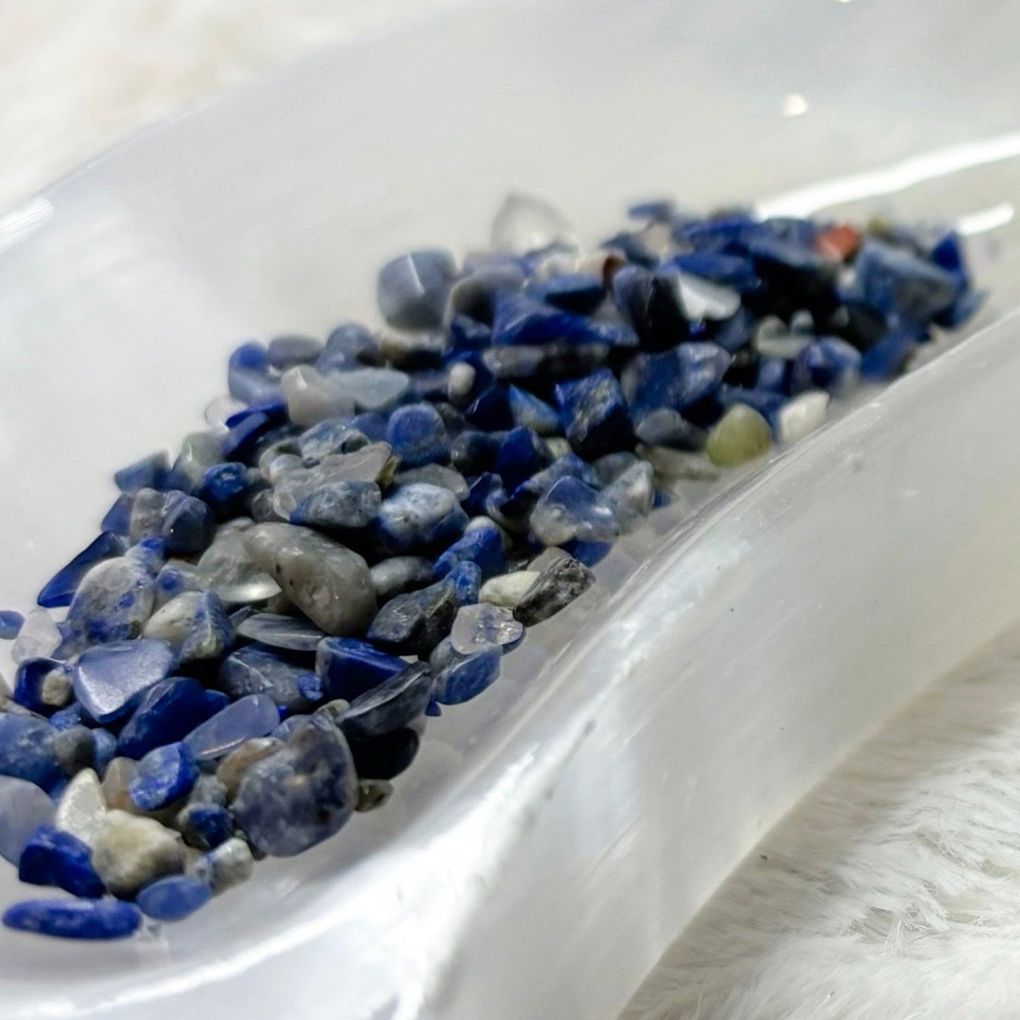 Small glass bottle labeled 'Blue Soda' with decorative stones on a white surface