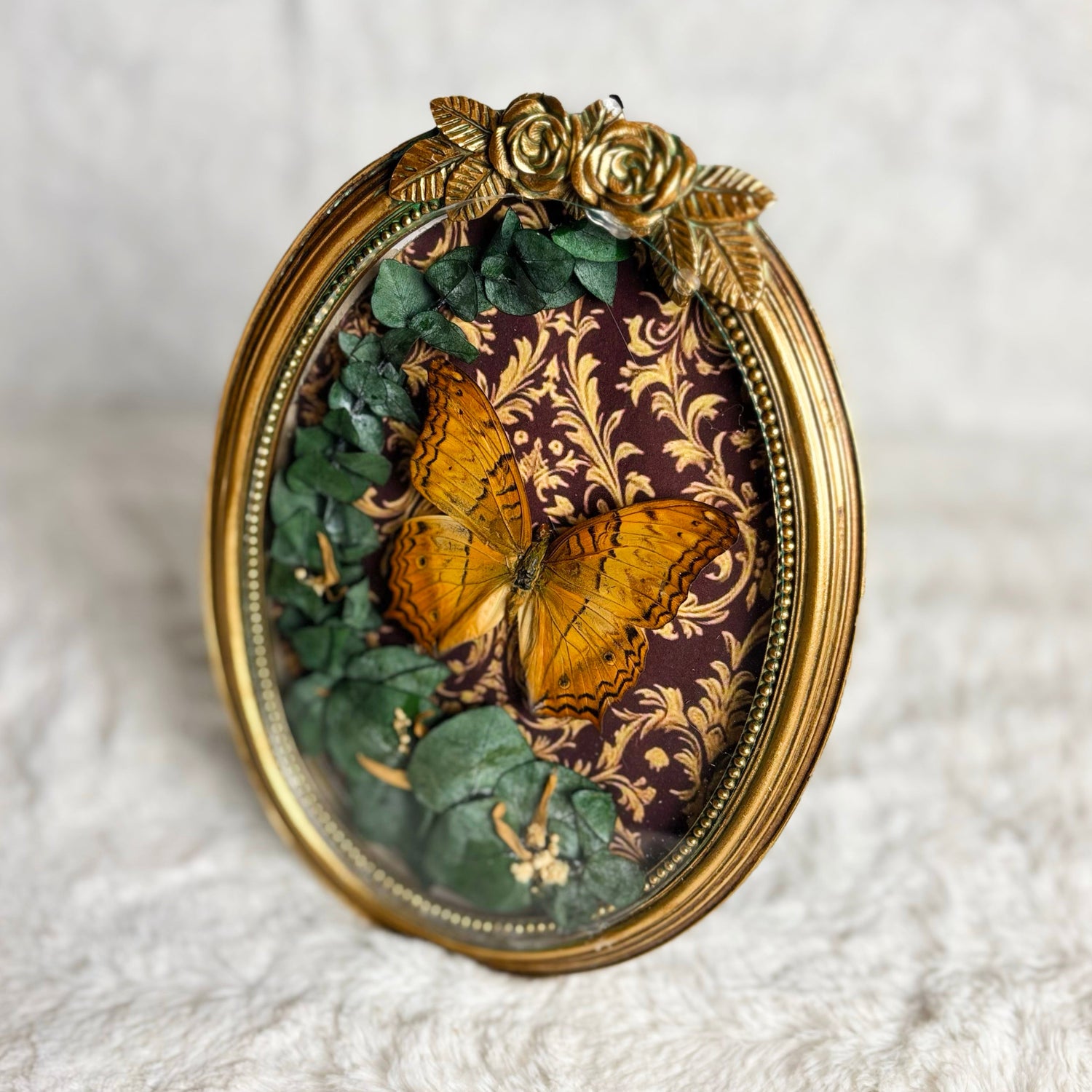 Decorative rose framed butterfly with leaves on a textured white surface