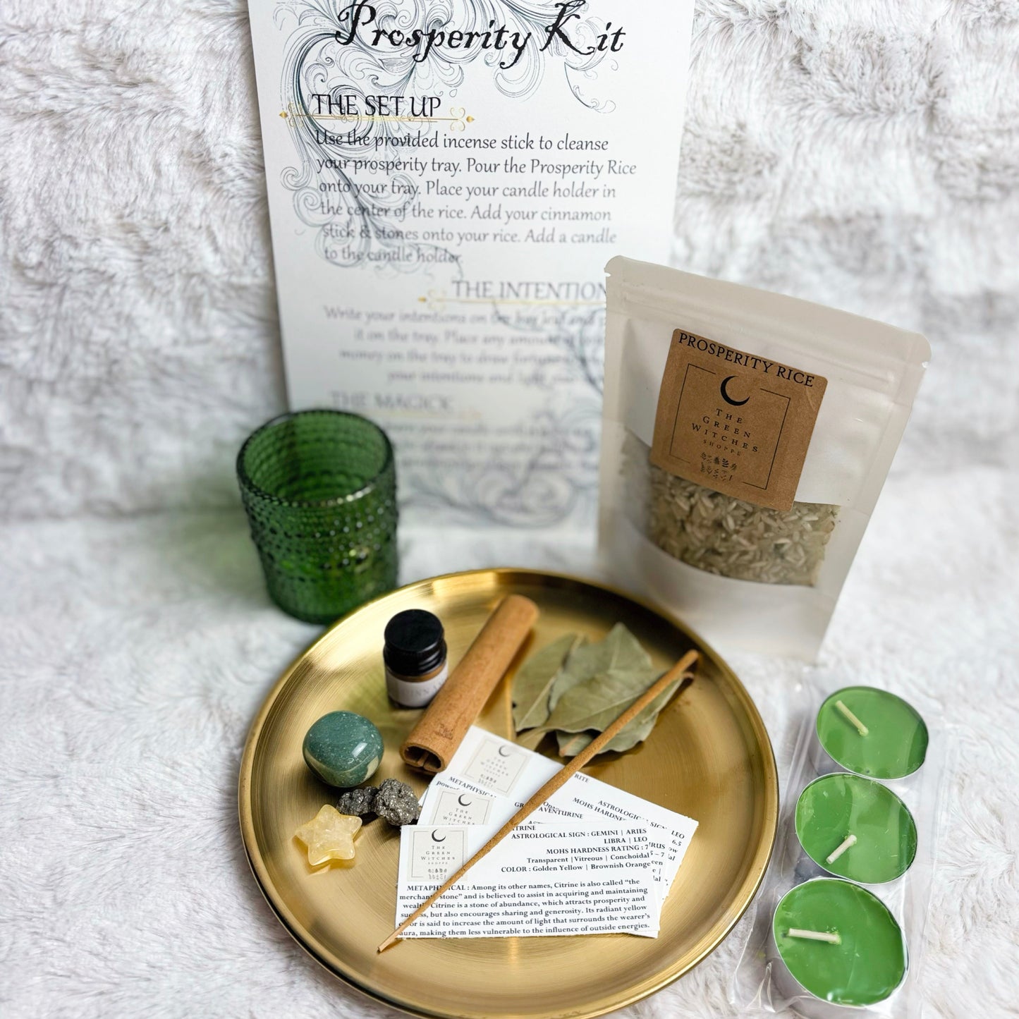  Prosperity kit with a gold tray, green candle, and other items on a textured white surface.