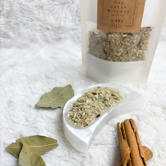 Herbal ingredients including cinnamon sticks and leaves on a white textured surface with a package labeled 'The Green Witches' in the background.