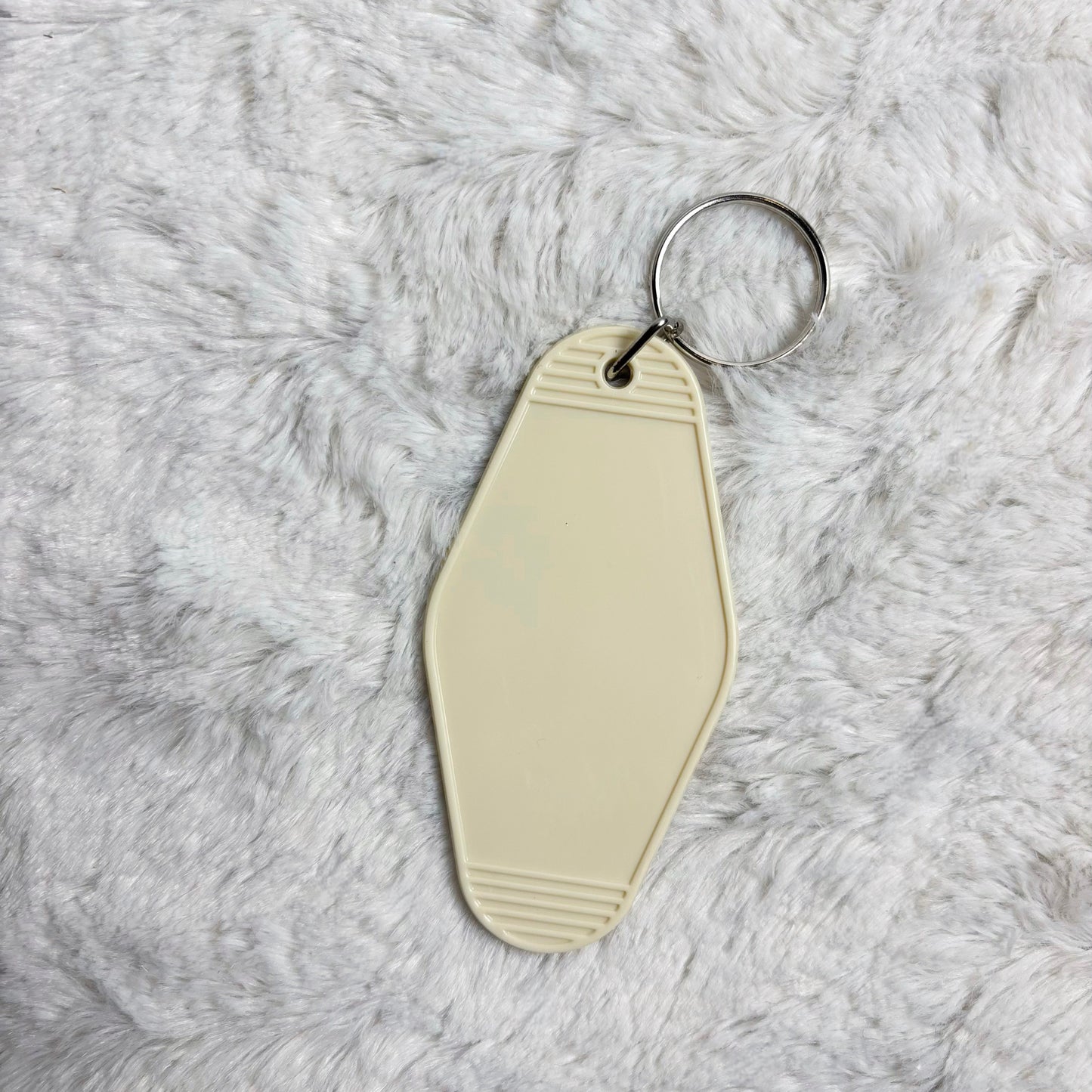 Beige keychain tag on a fluffy gray surface