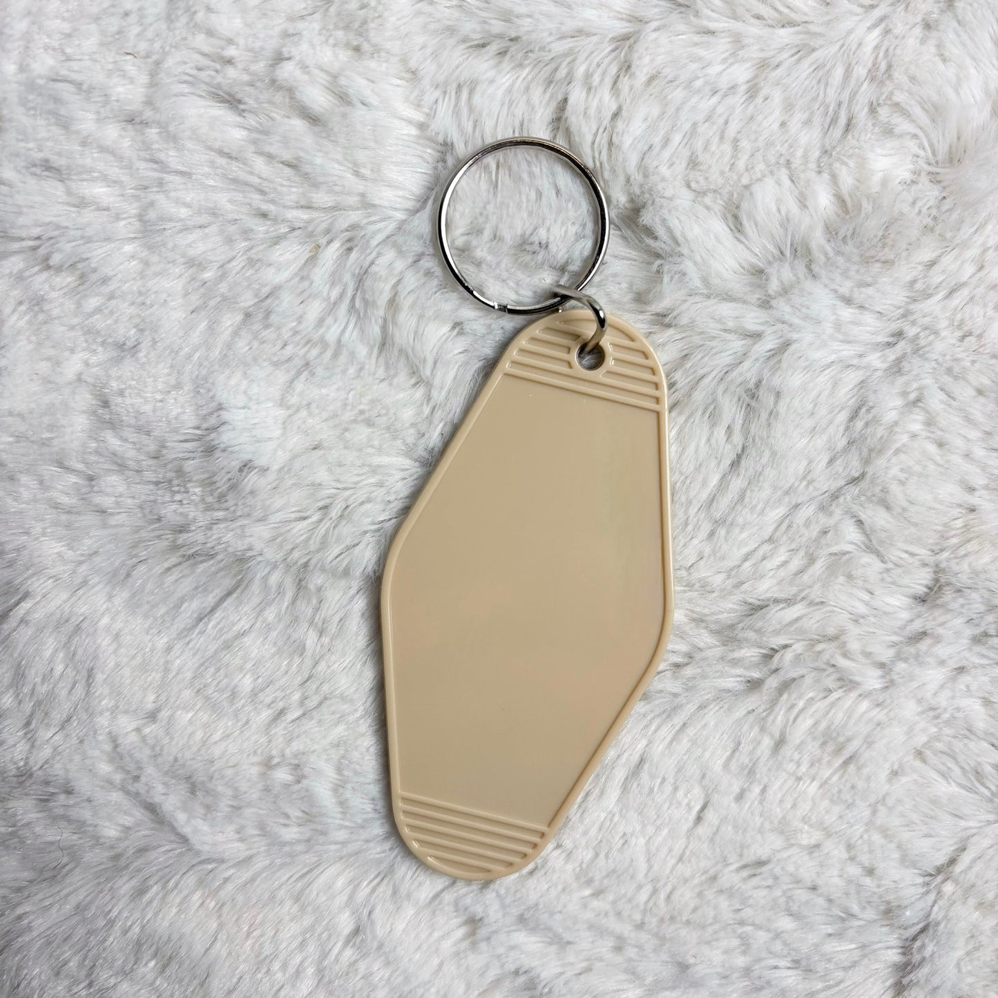 Beige keychain tag on a fluffy white surface