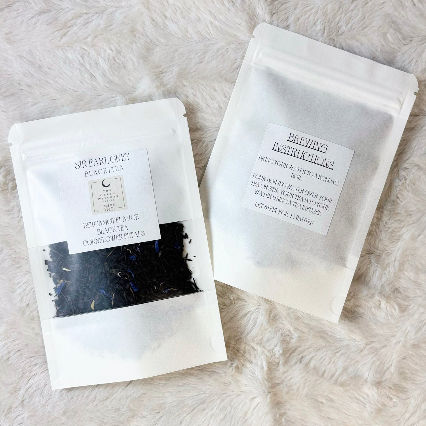 Two white packages with black text on a light gray fur surface