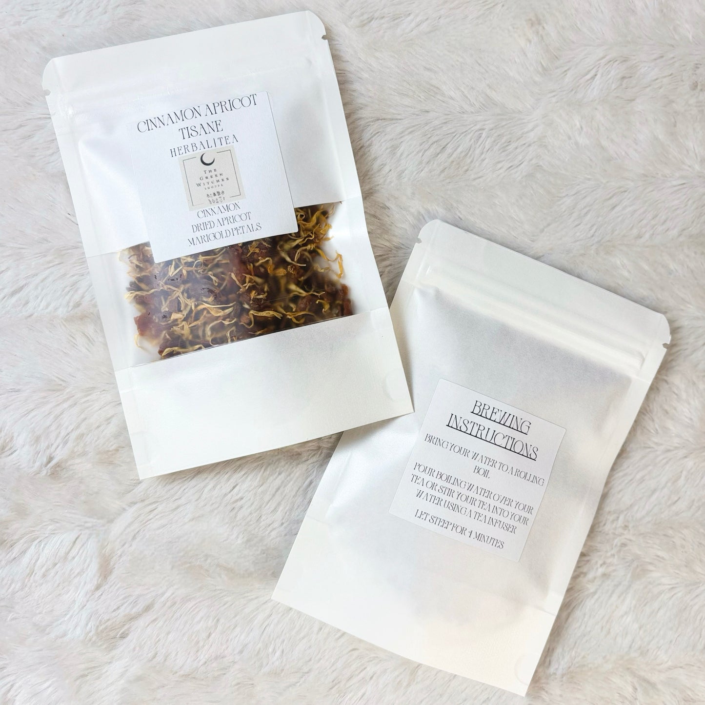 Two white packages with tea on a textured white surface