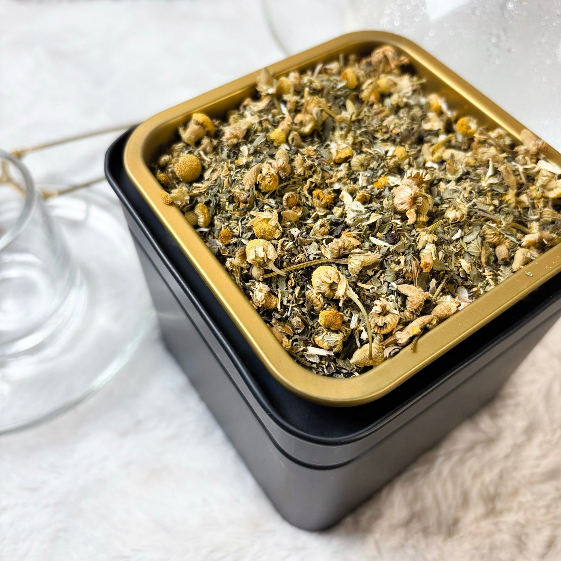 Square container with dried herbs on a white surface