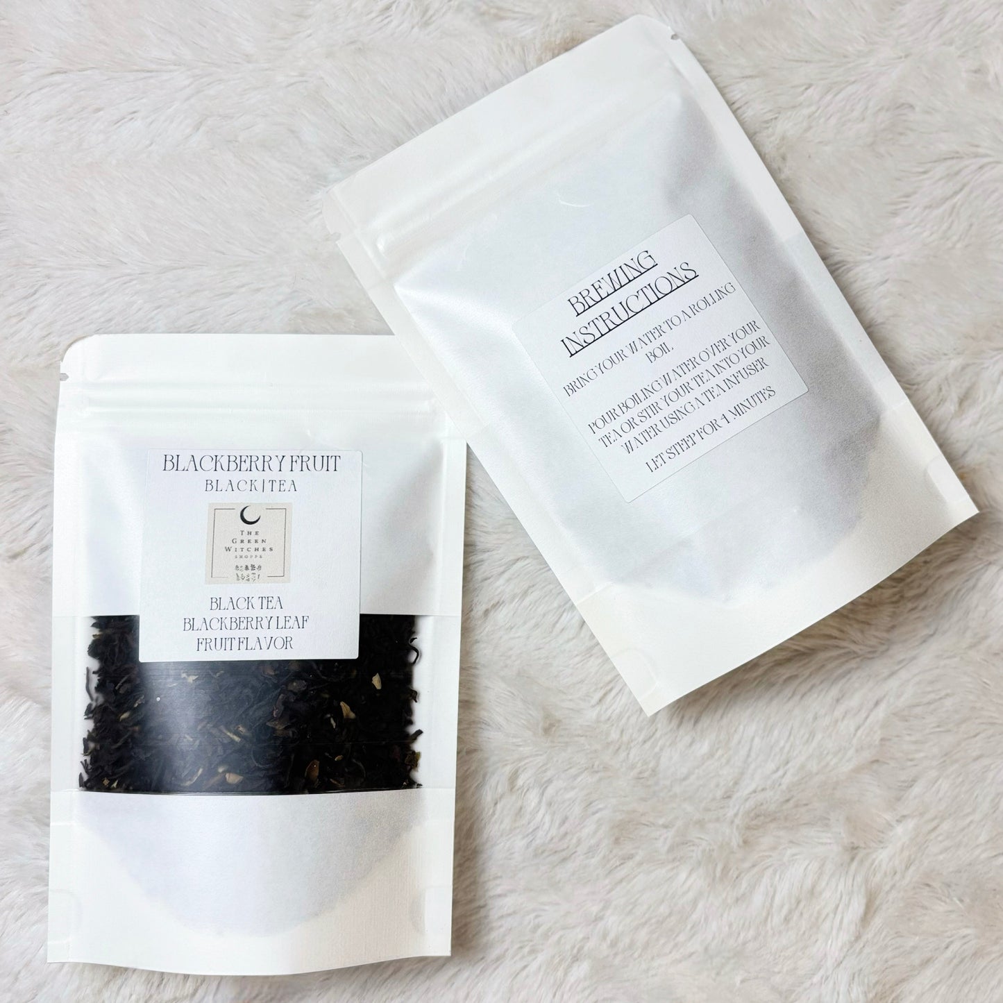 Two black tea packages on a light stone surface