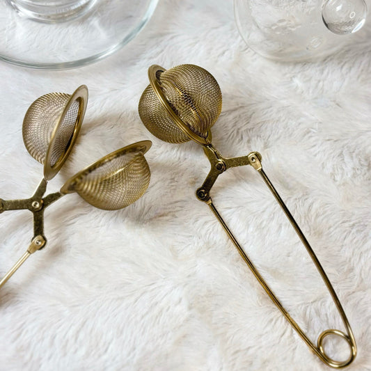 Gold tea infuser on a white background