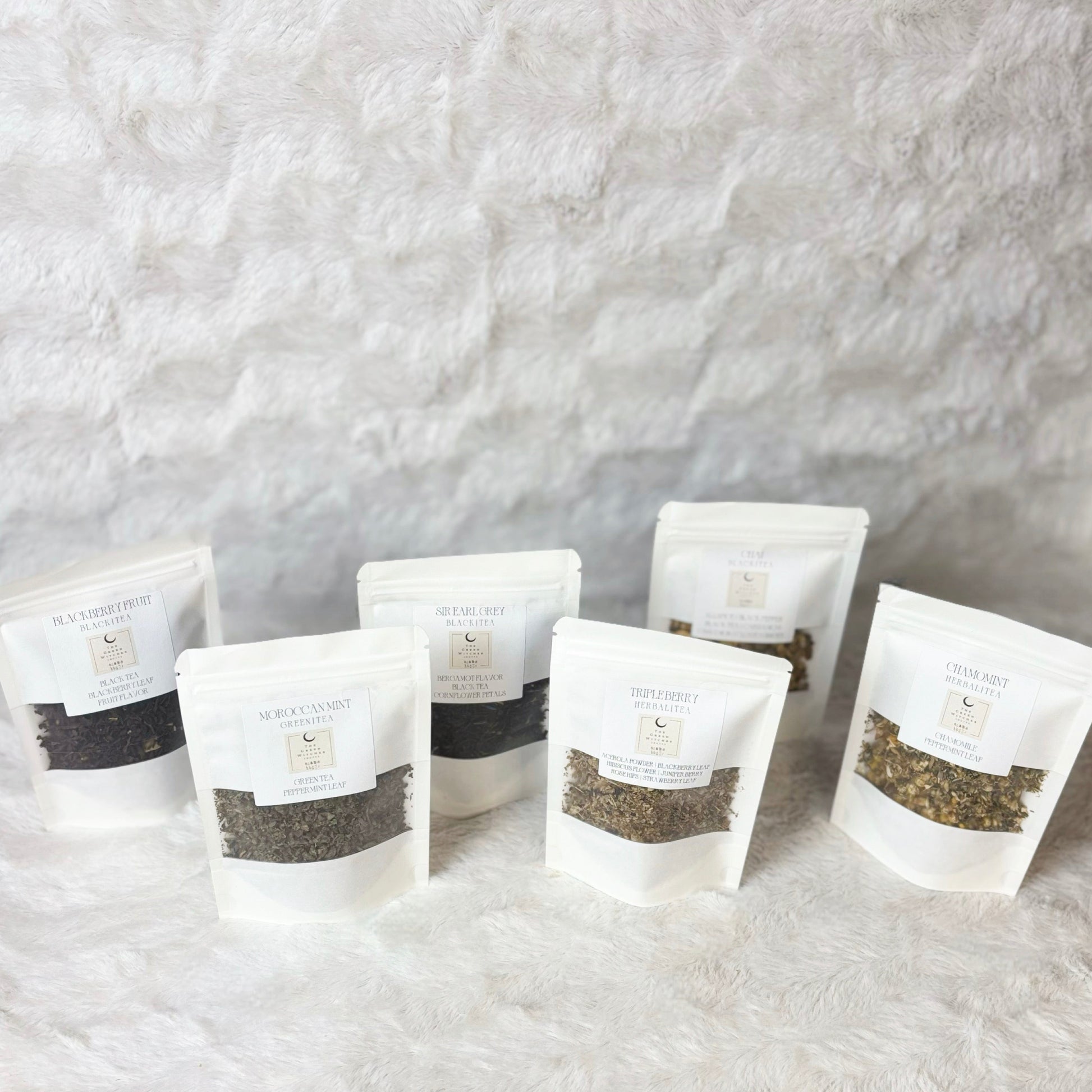 Set of white tea bags with visible tea leaves on a textured gray background
