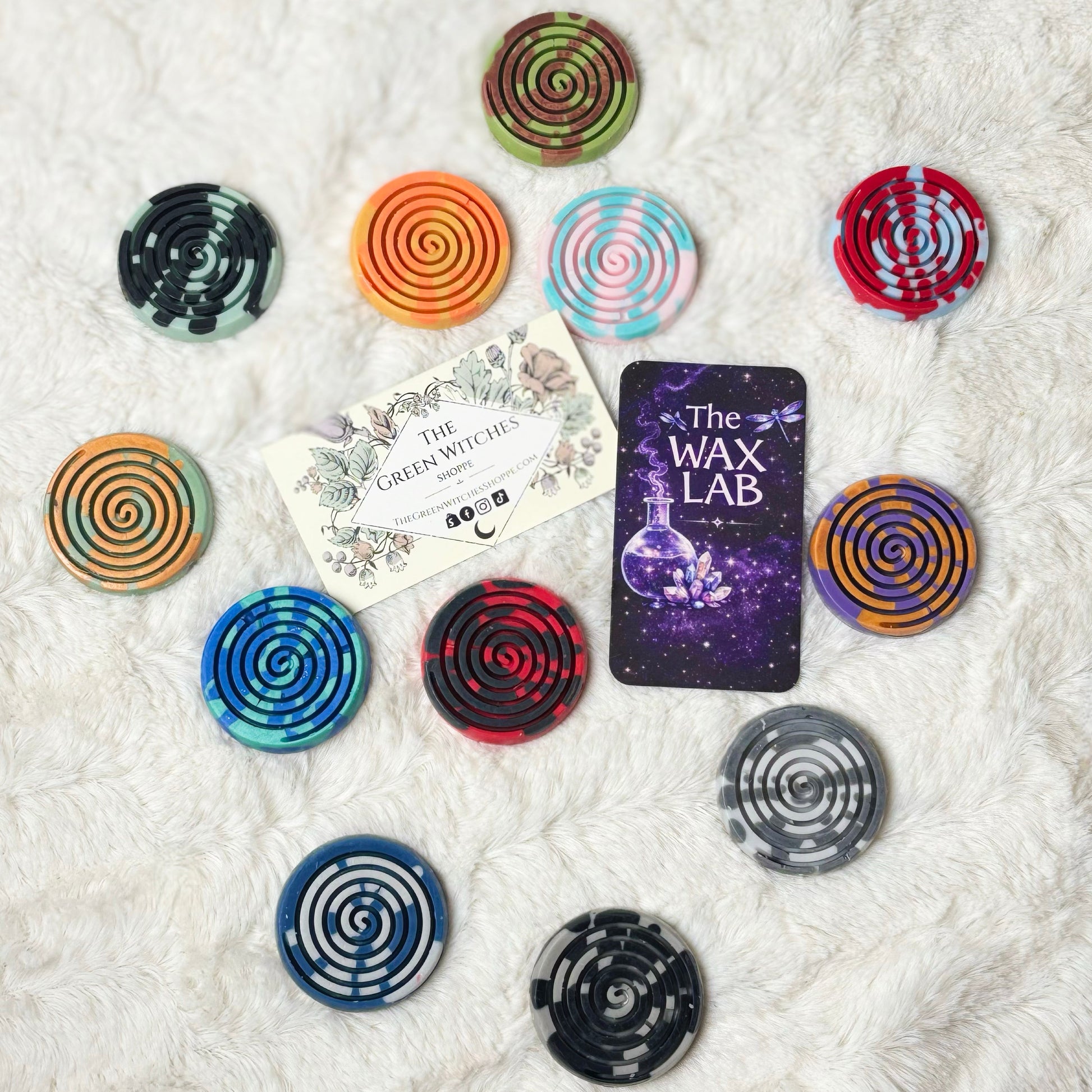 Colorful spiral-shaped wax melts on a textured white surface with 'The Wax Lab' branding.