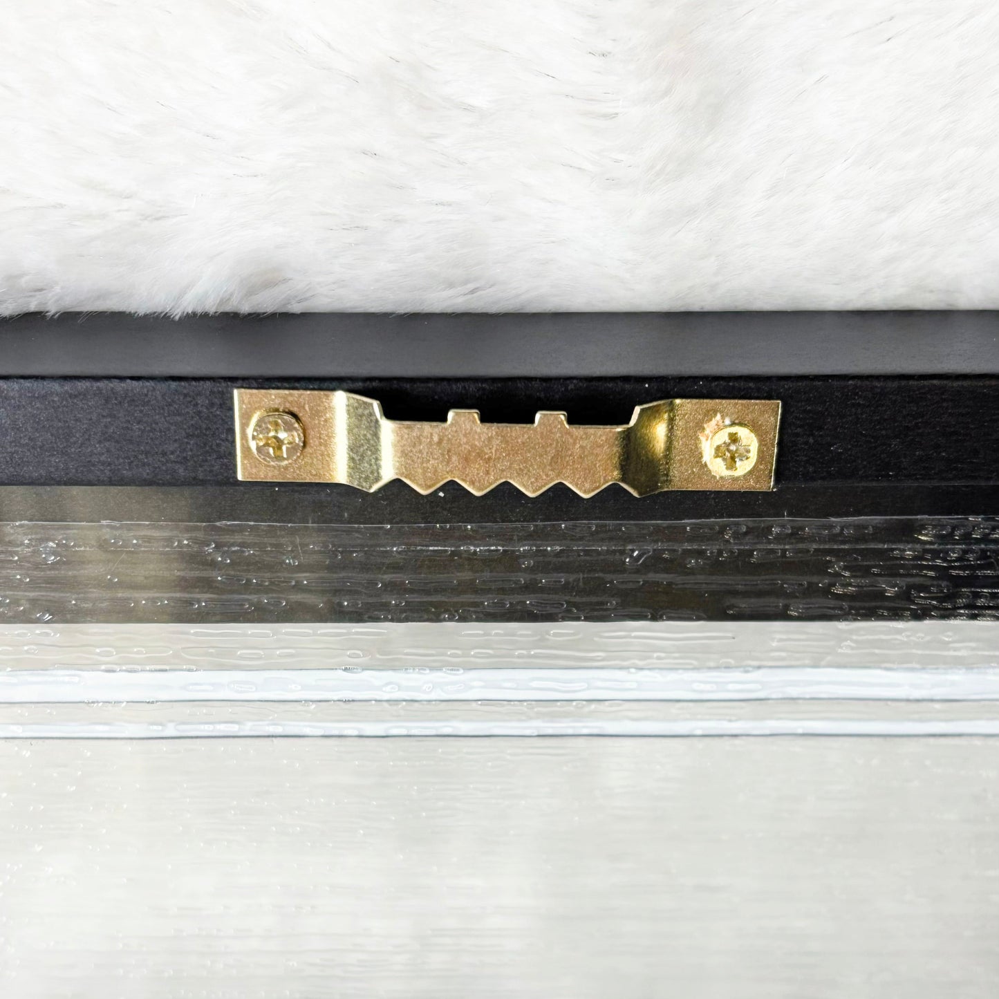 Gold hook on the back of a picture with a white background