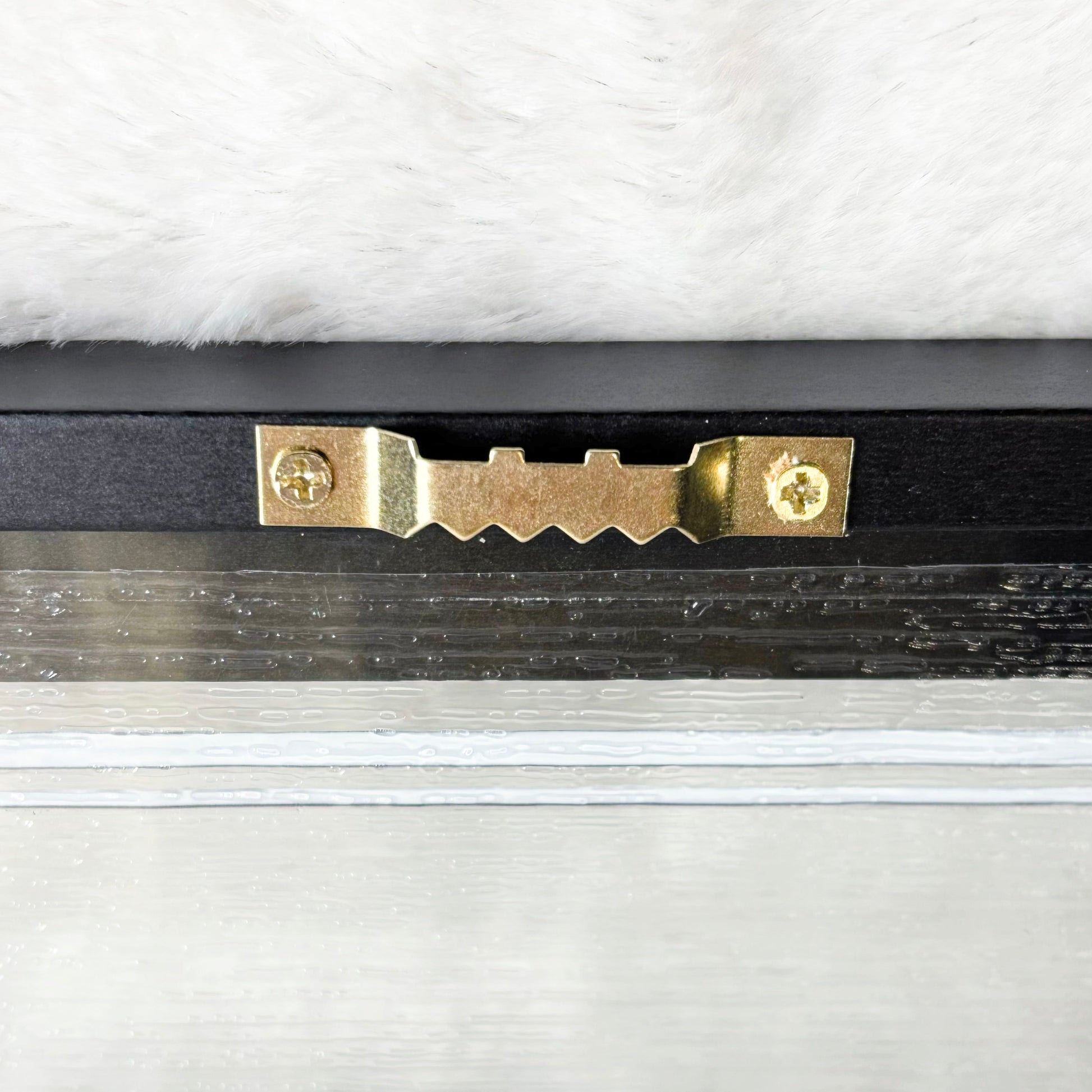 Gold hook on the back of a picture with a white background