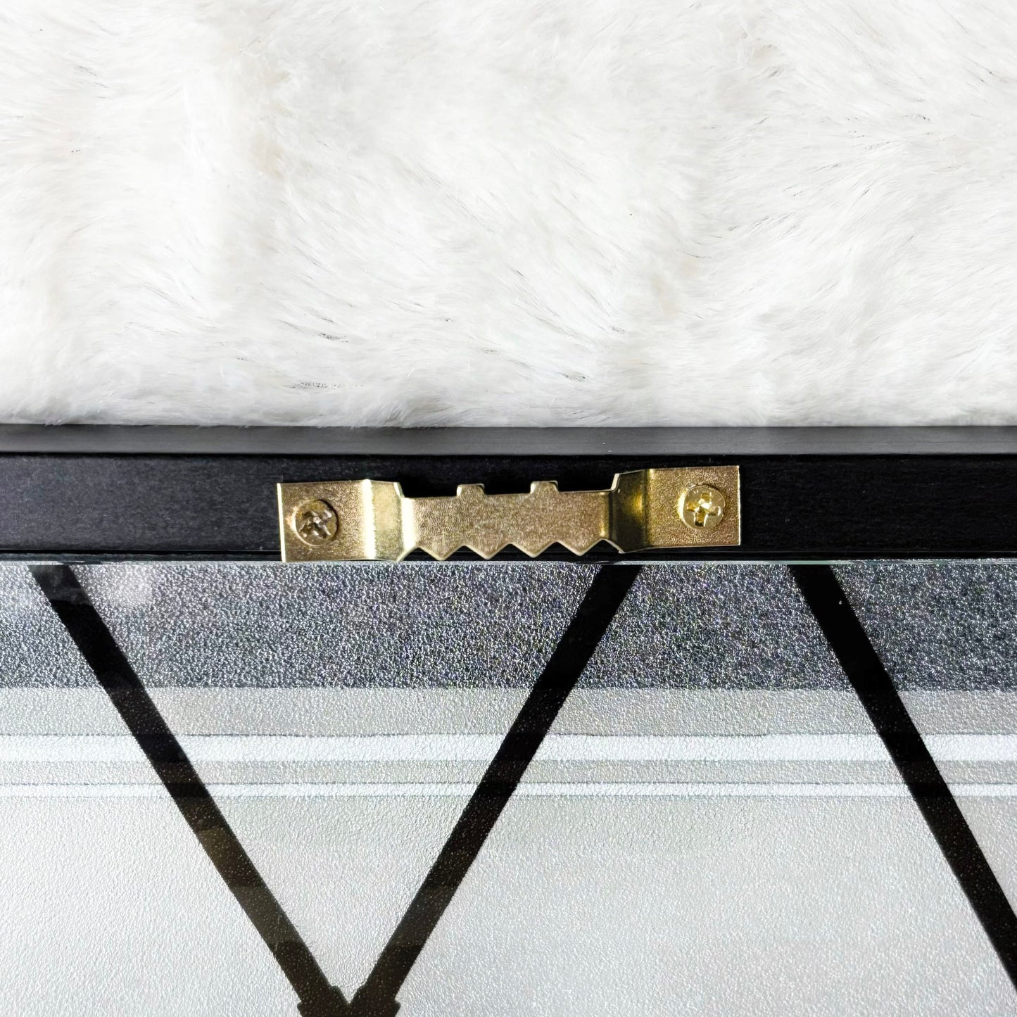Close-up of a black metal frame with gold hardware on a white marble surface.
