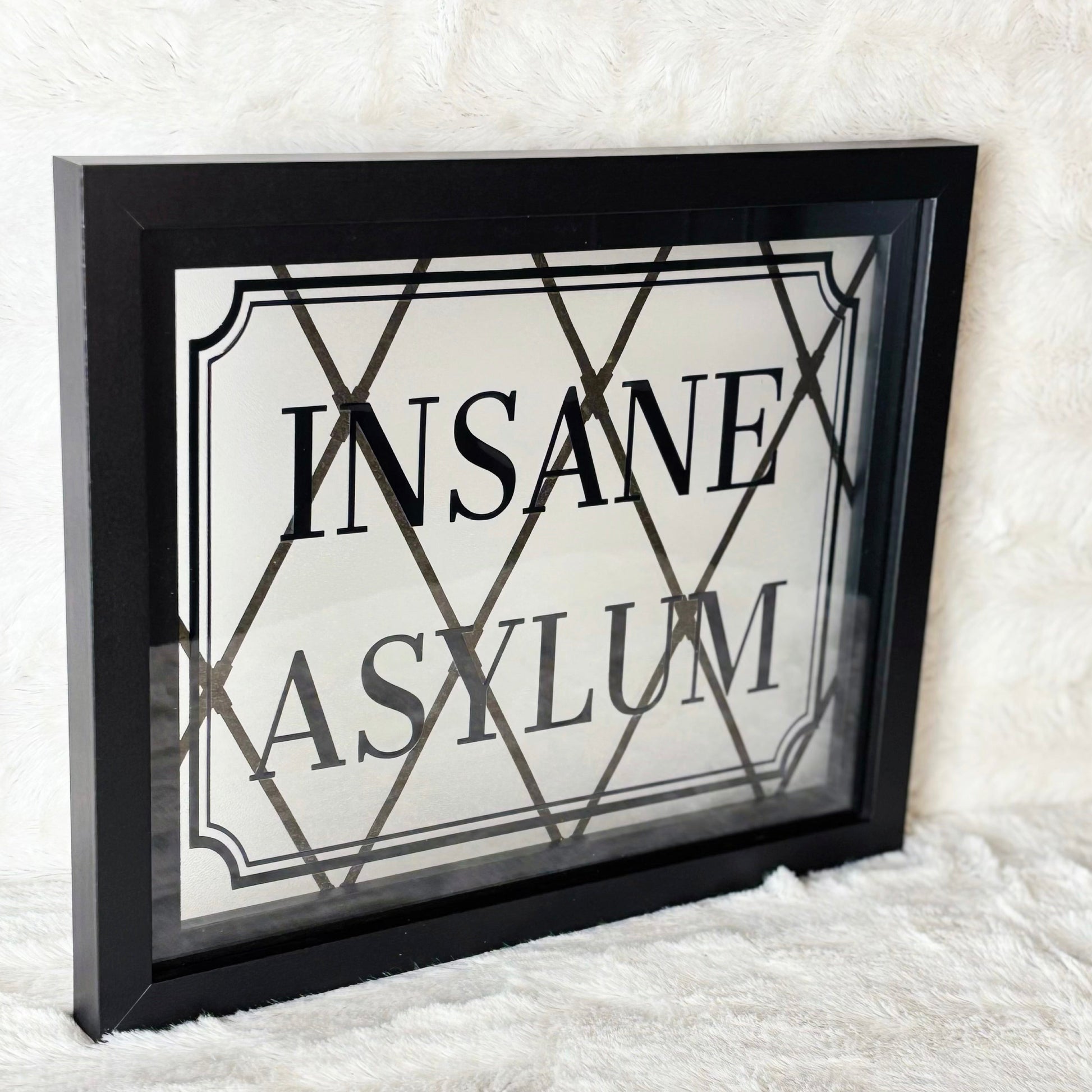 Framed sign with 'INSANE ASYLUM' text on a textured white background