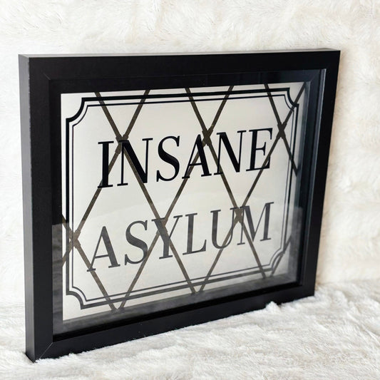 Framed sign with 'INSANE ASYLUM' text on a textured white background