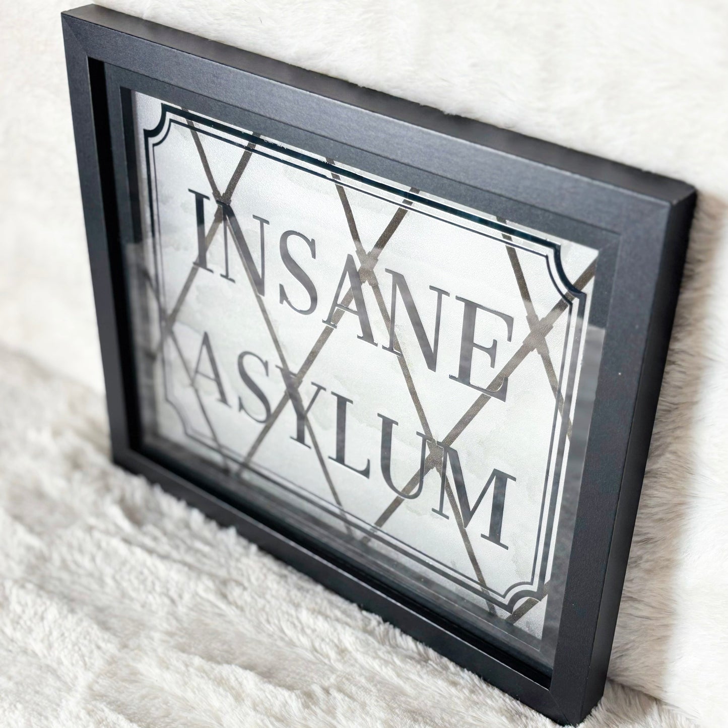 Framed sign with 'Insane Asylum' text on a white textured surface