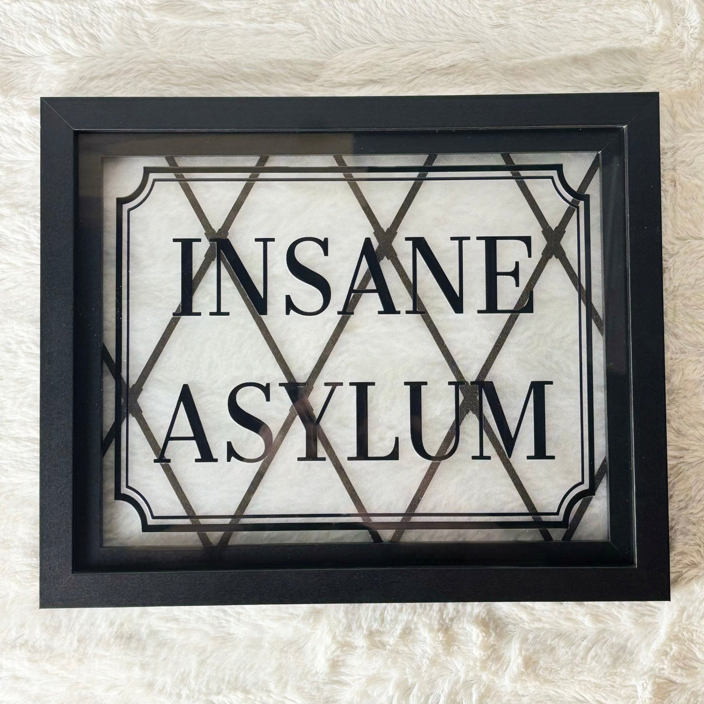 Framed sign with 'INSANE ASYLUM' text on a textured white background