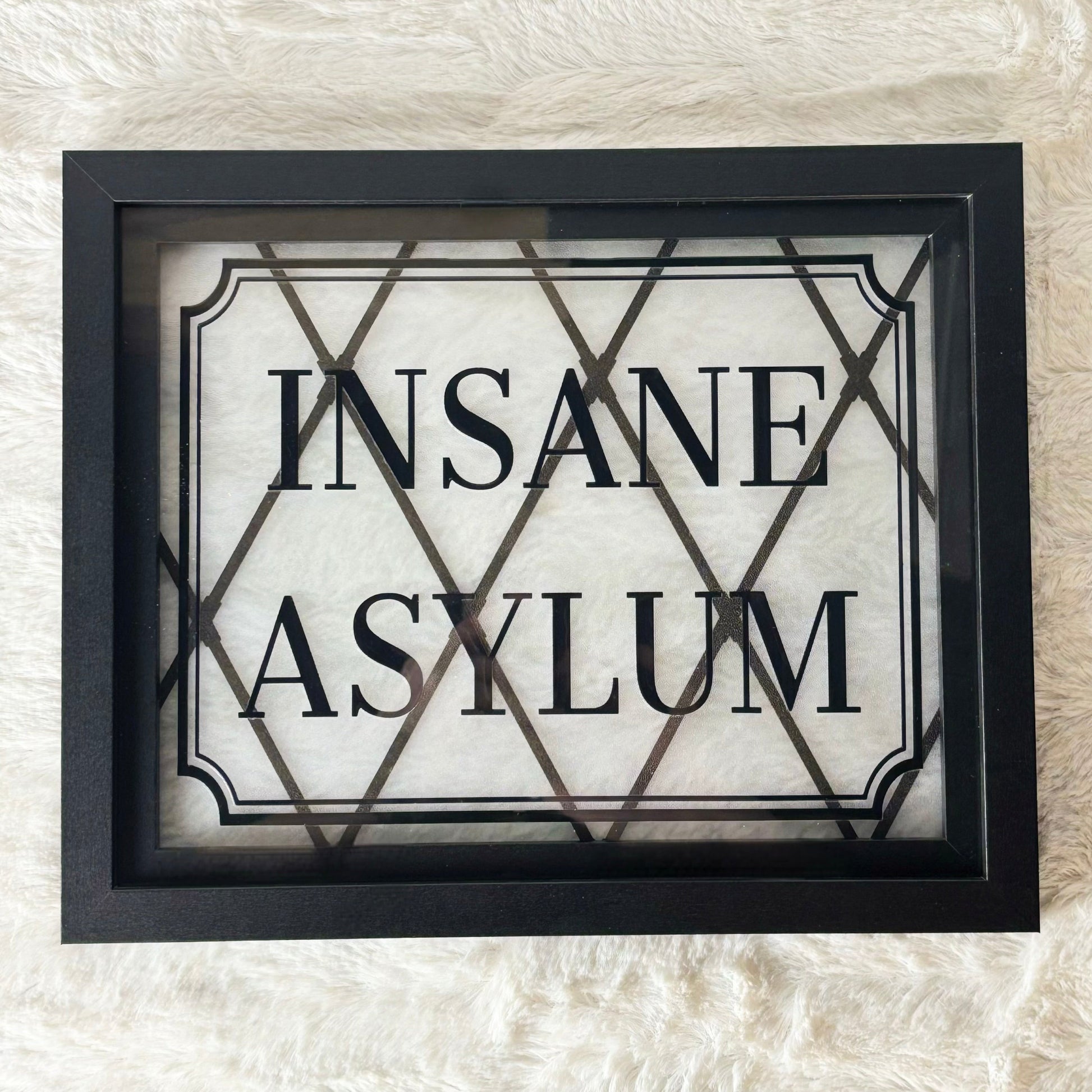 Framed sign with 'INSANE ASYLUM' text on a textured white background