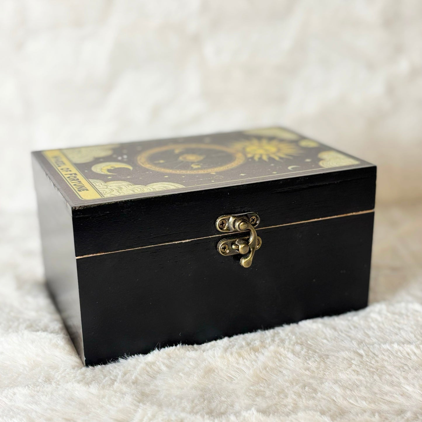 Black decorative box with gold accents on a white textured surface