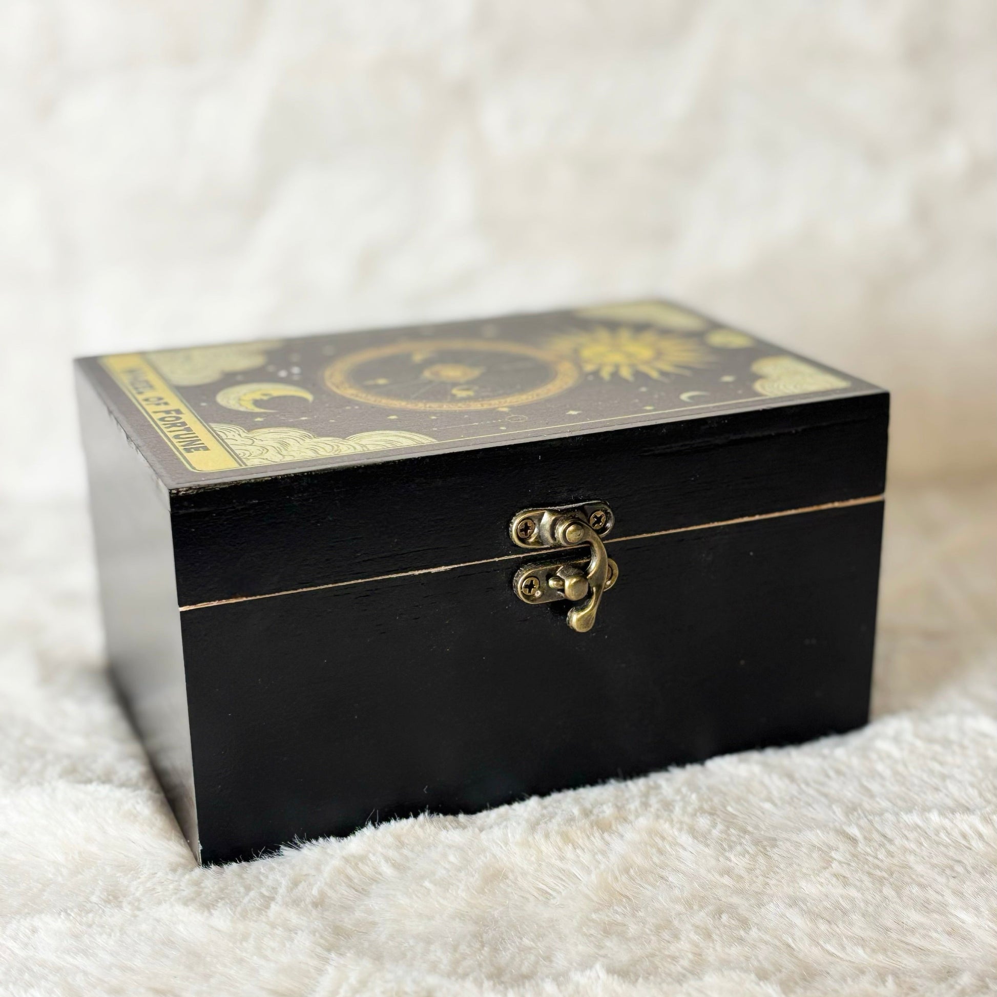 Black decorative box with gold accents on a white textured surface