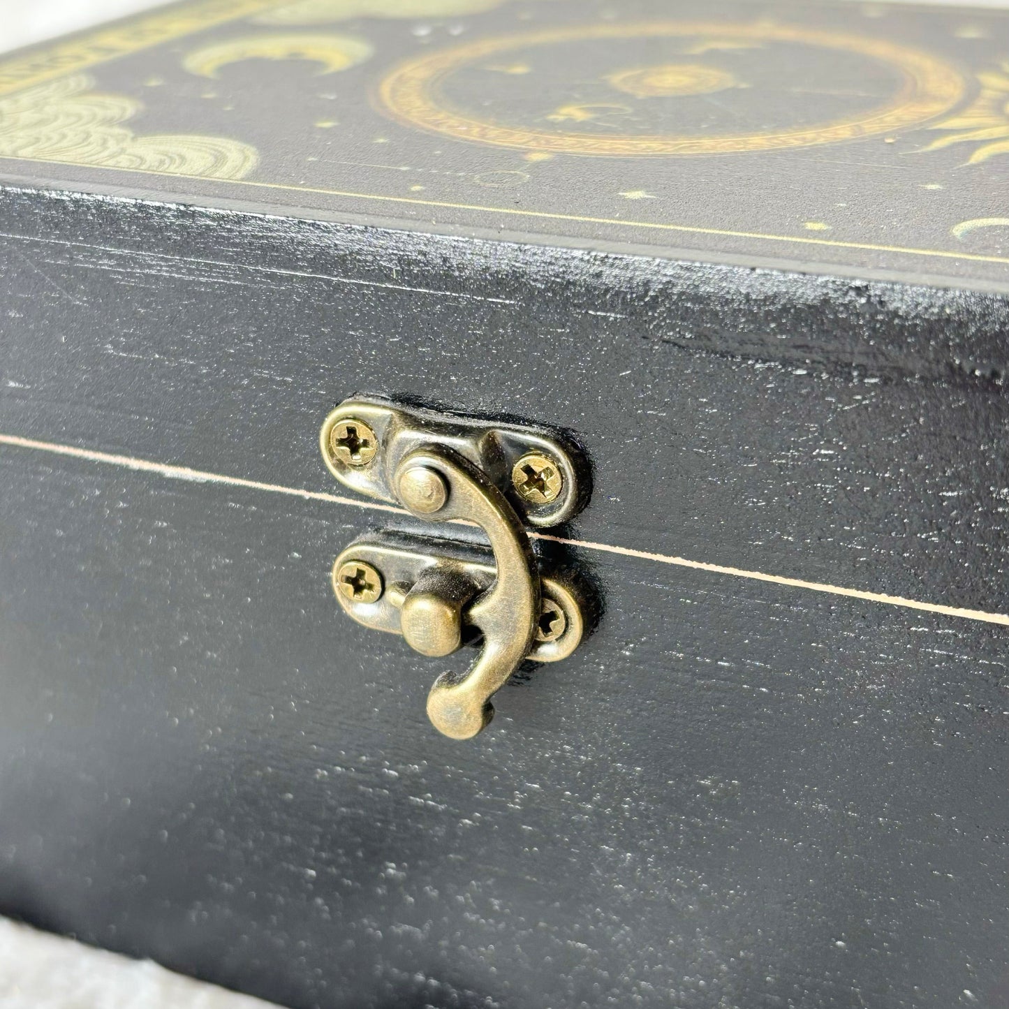 Black decorative box with gold accents and a brass latch on a white background