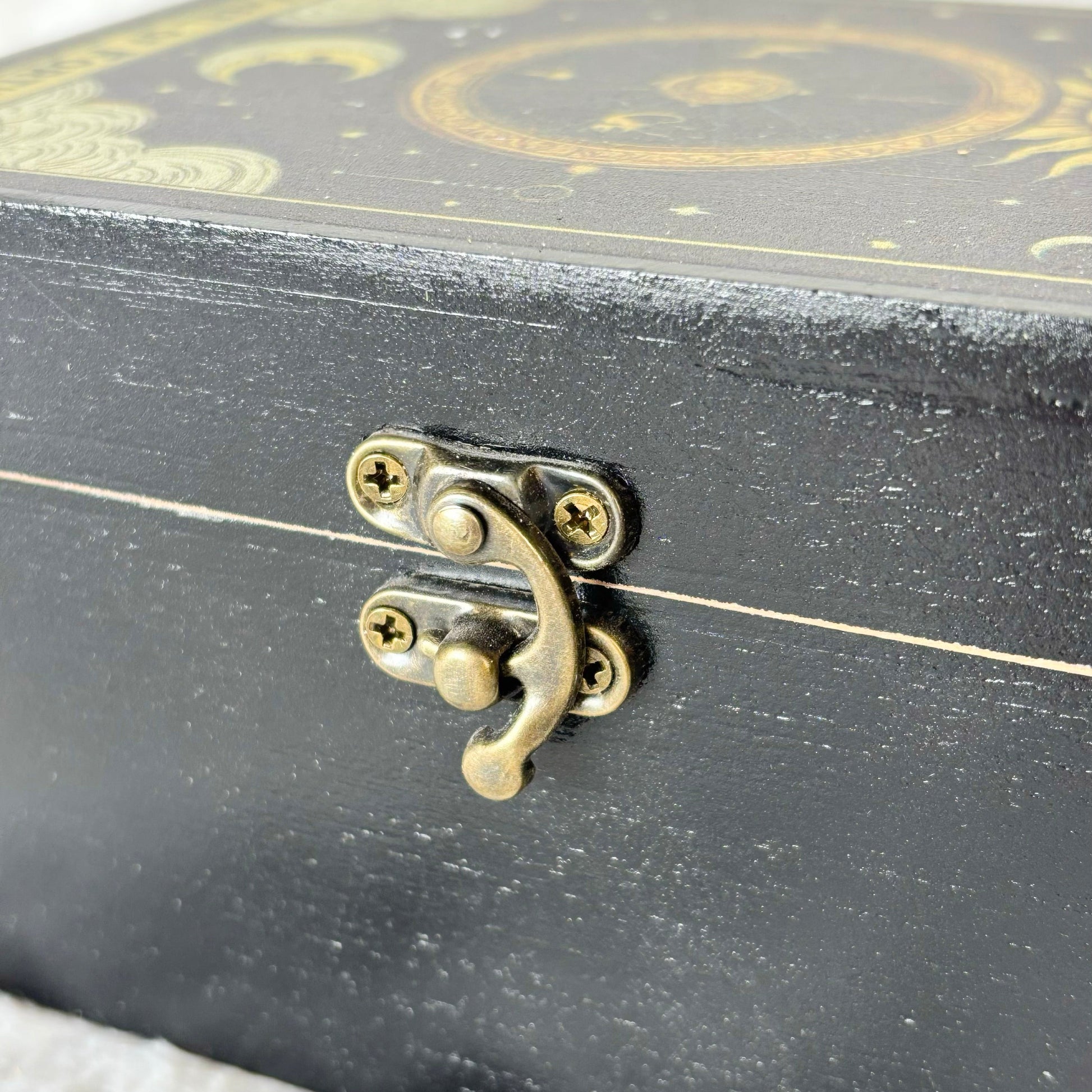 Black decorative box with gold accents and a brass latch on a white background