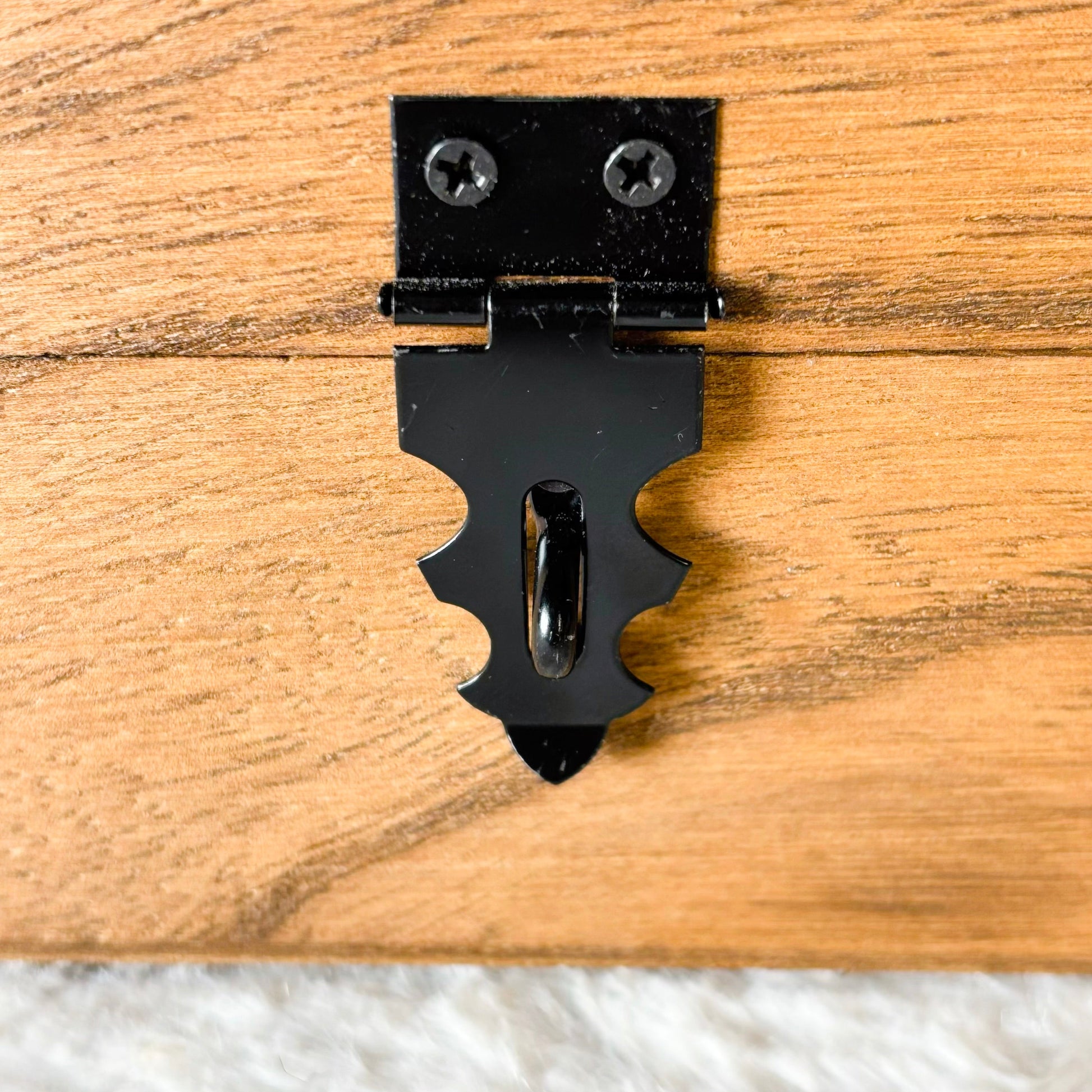Black decorative metal latch on a wooden surface