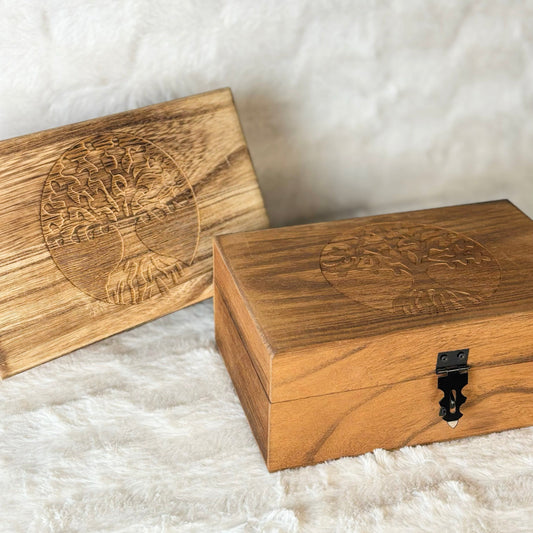 Two wooden boxes with engraved designs on a textured white surface