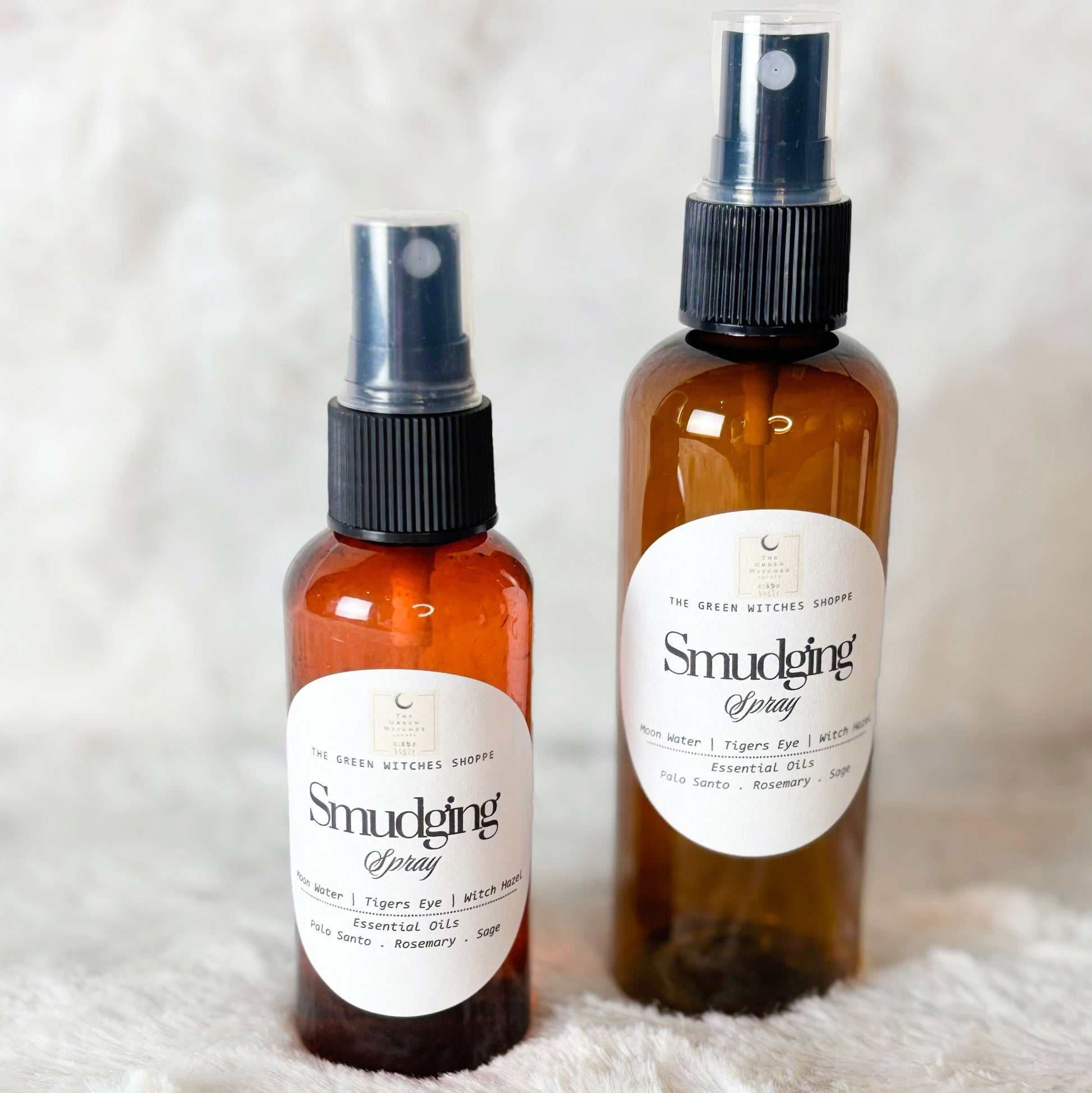 Two bottles of 'Smudging' spray on a white fluffy surface