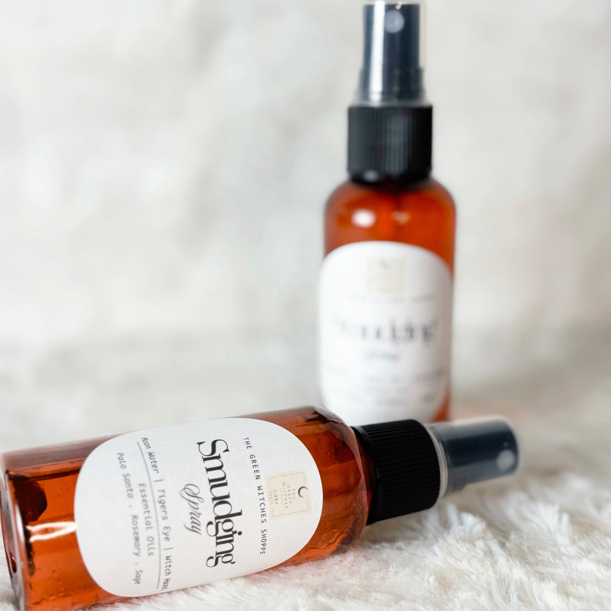 Two brown spray bottles with white labels on a white fur surface.