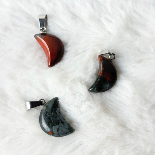 Three moon-shaped pendants on a white textured surface