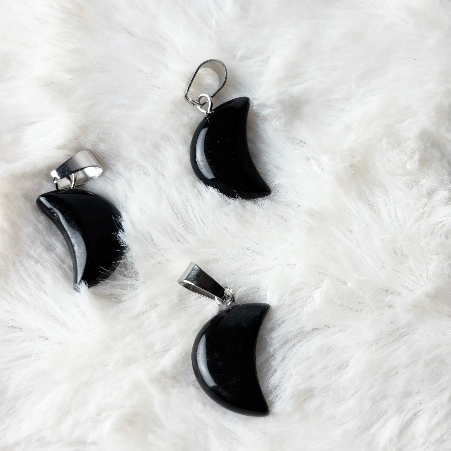 Black crescent moon-shaped earrings on a white fur surface