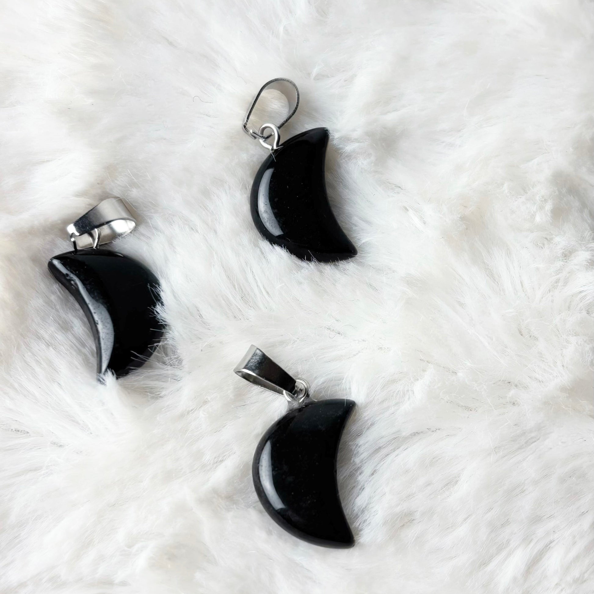 Black crescent moon-shaped earrings on a white fur surface
