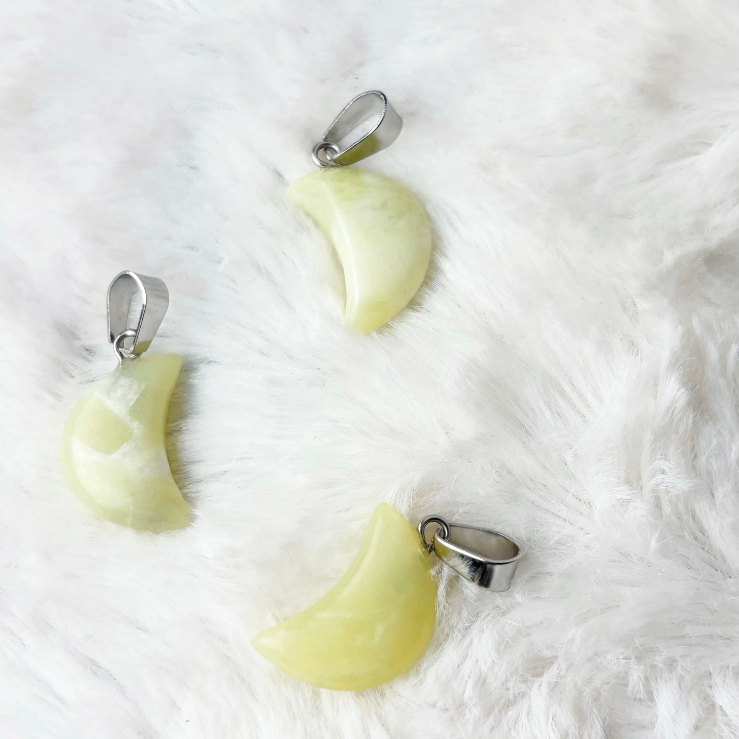 Three moon-shaped pendants on a white fur background