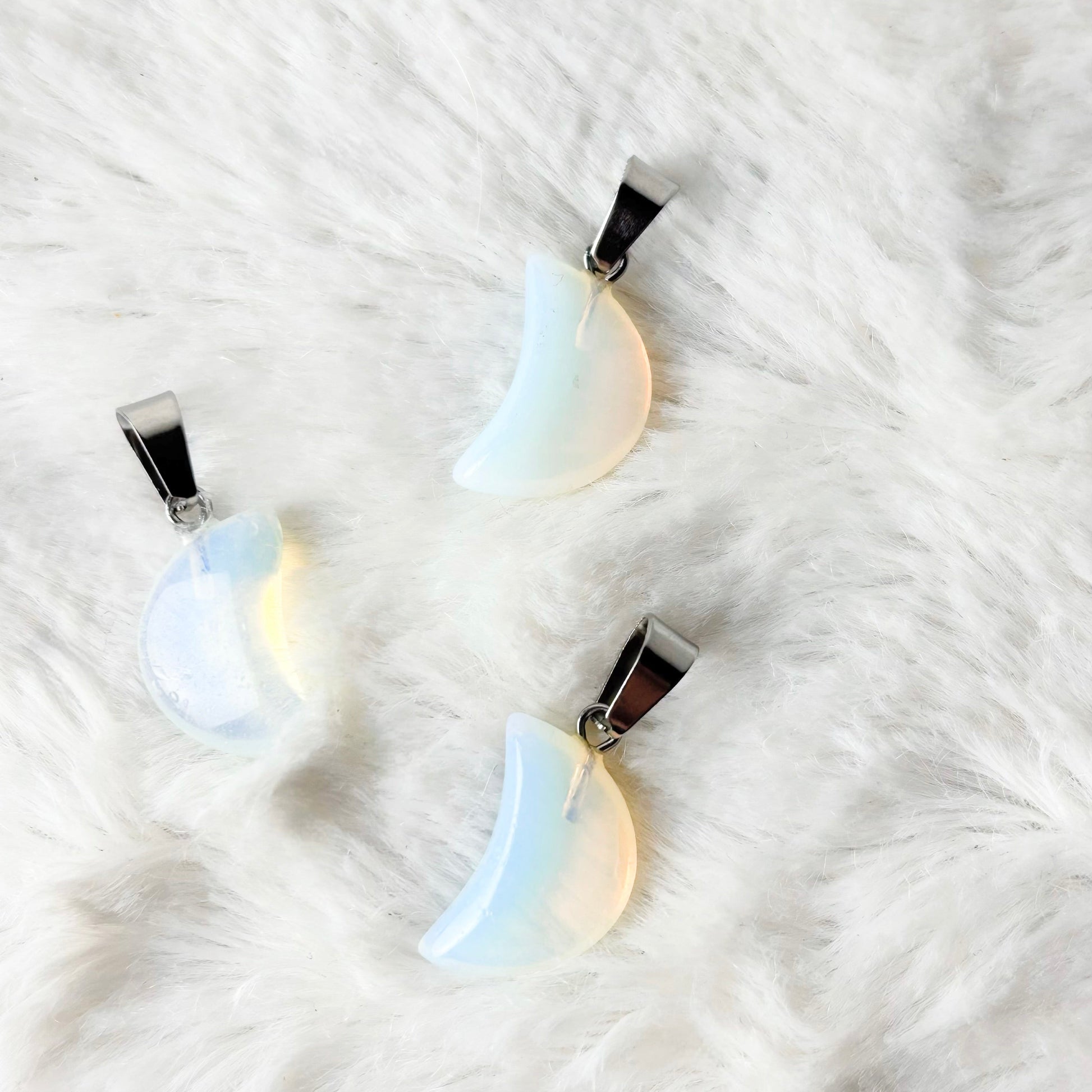 Three moon-shaped pendants on a white fur background