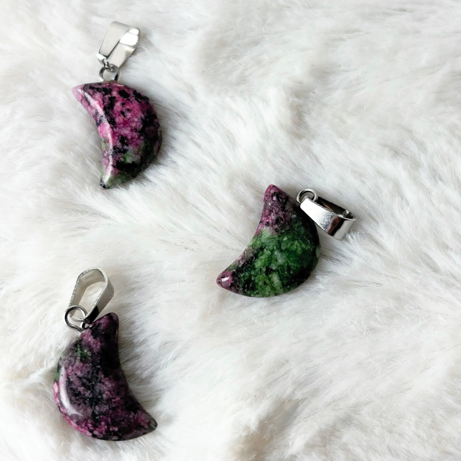 Three stone pendants on a white fur surface