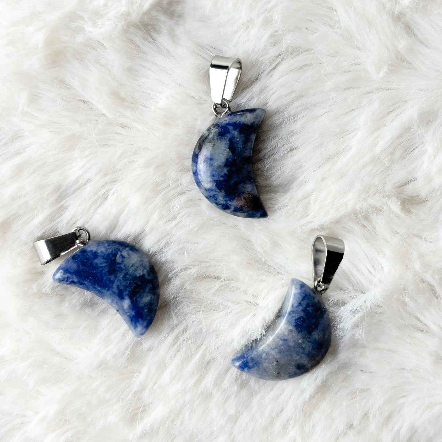 Three blue stone pendants on a white fur surface