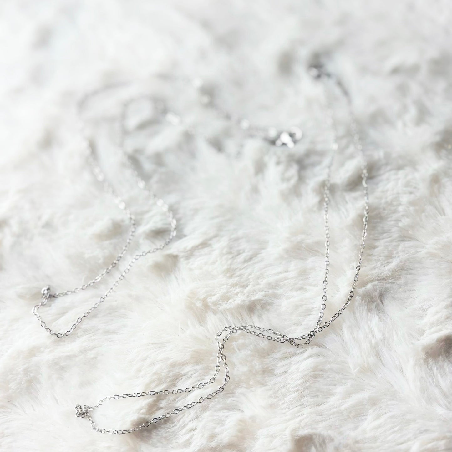 Silver necklace on a white fur surface