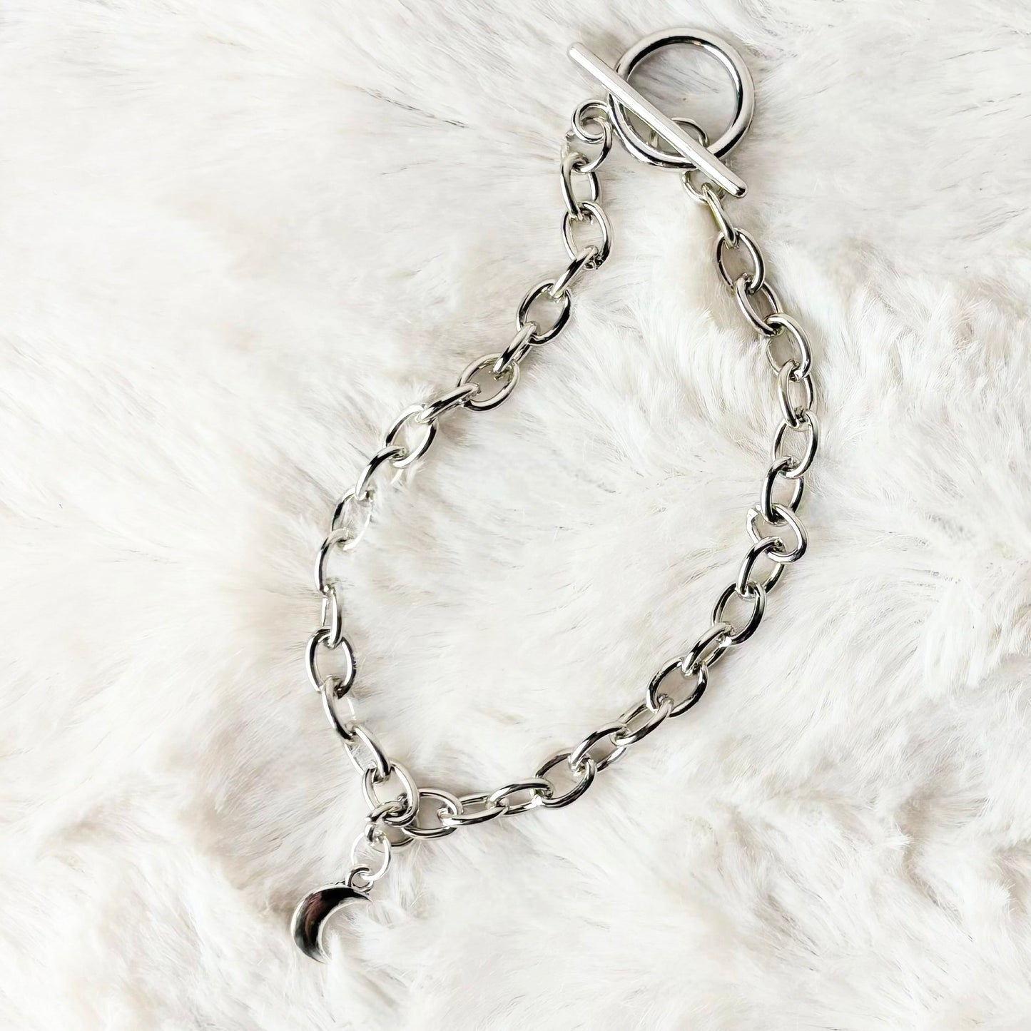 Silver chain bracelet on a white fur surface