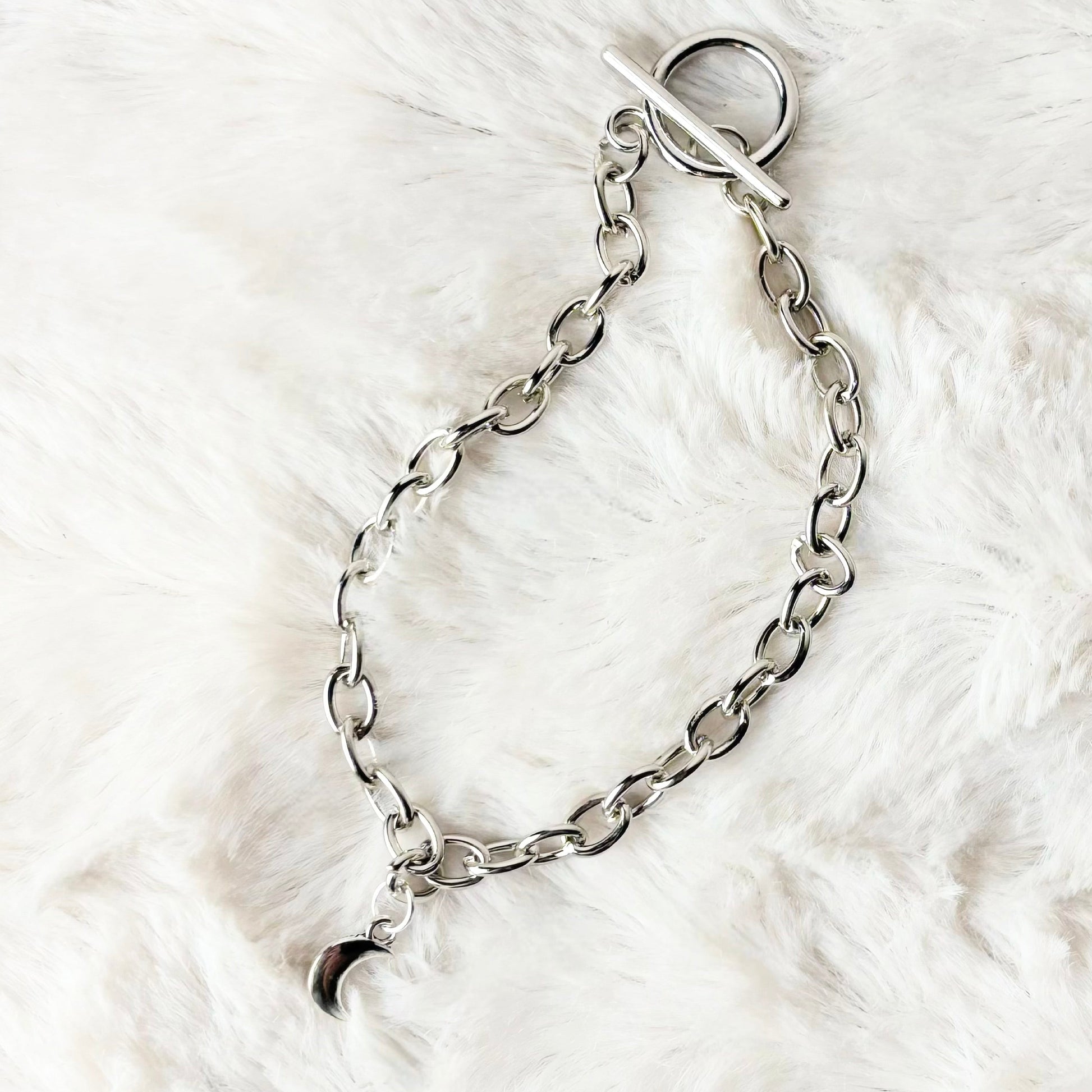 Silver chain bracelet on a white fur surface