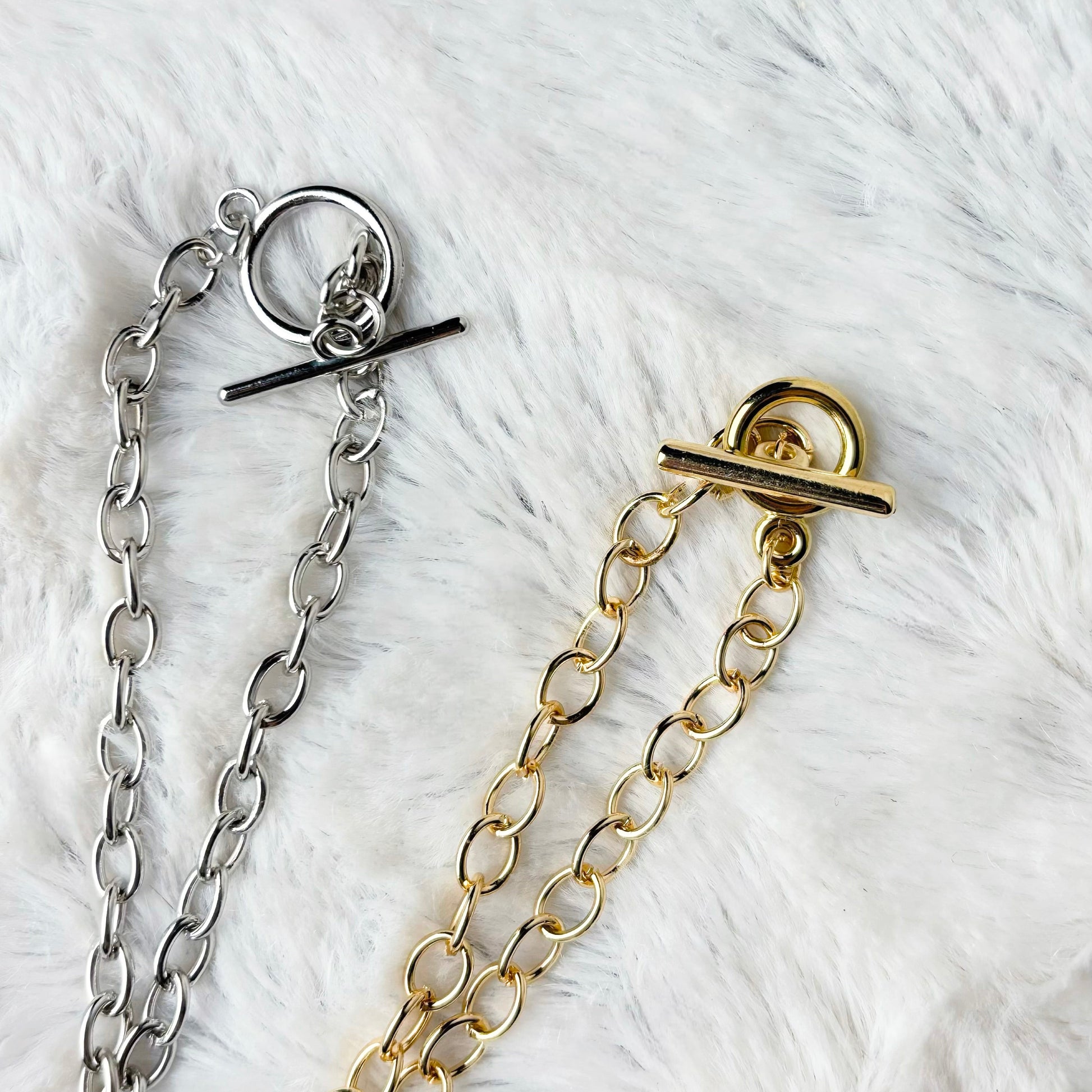 Gold and silver chain clasps on a white fur background
