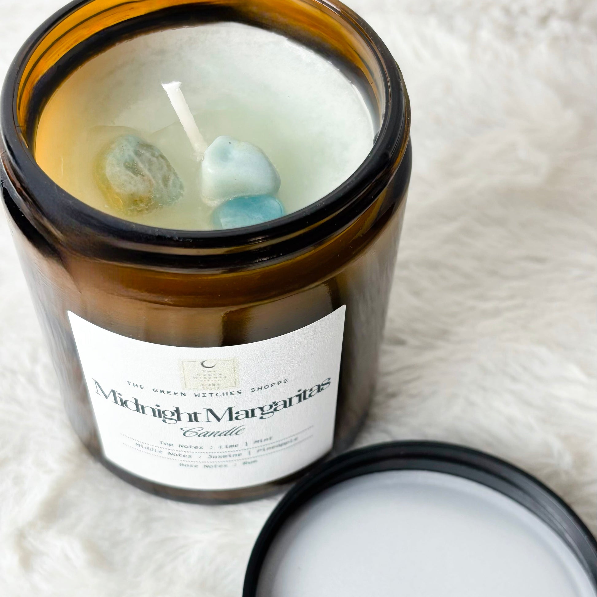 Candle in an amber jar with a label on a white textured surface